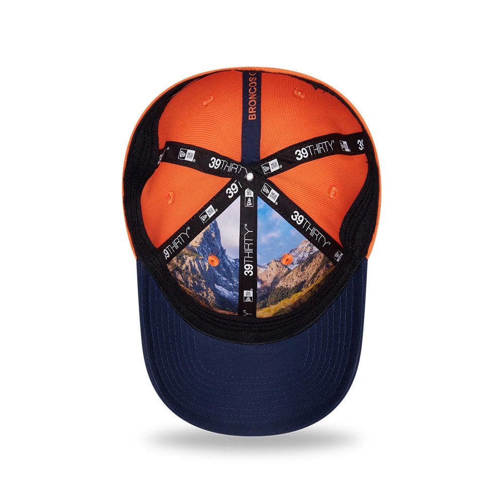 Broncos NFL Draft 2026 Orange New Era 39THIRTY M-Crown Stretch Fit Cap, inside view showing a scenic mountain print on the crown panel taping, black sweatband near the blue undervisor, and orange crown panels with small embroidered eyelets.