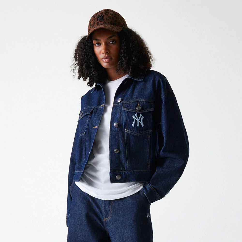 New Era New York Yankees Womens MLB Denim Dark Blue Jacket, front view on-model showing a buttoned dark blue denim design featuring an embroidered New York Yankees logo on the chest pocket, styled with a white top and dark denim trousers.