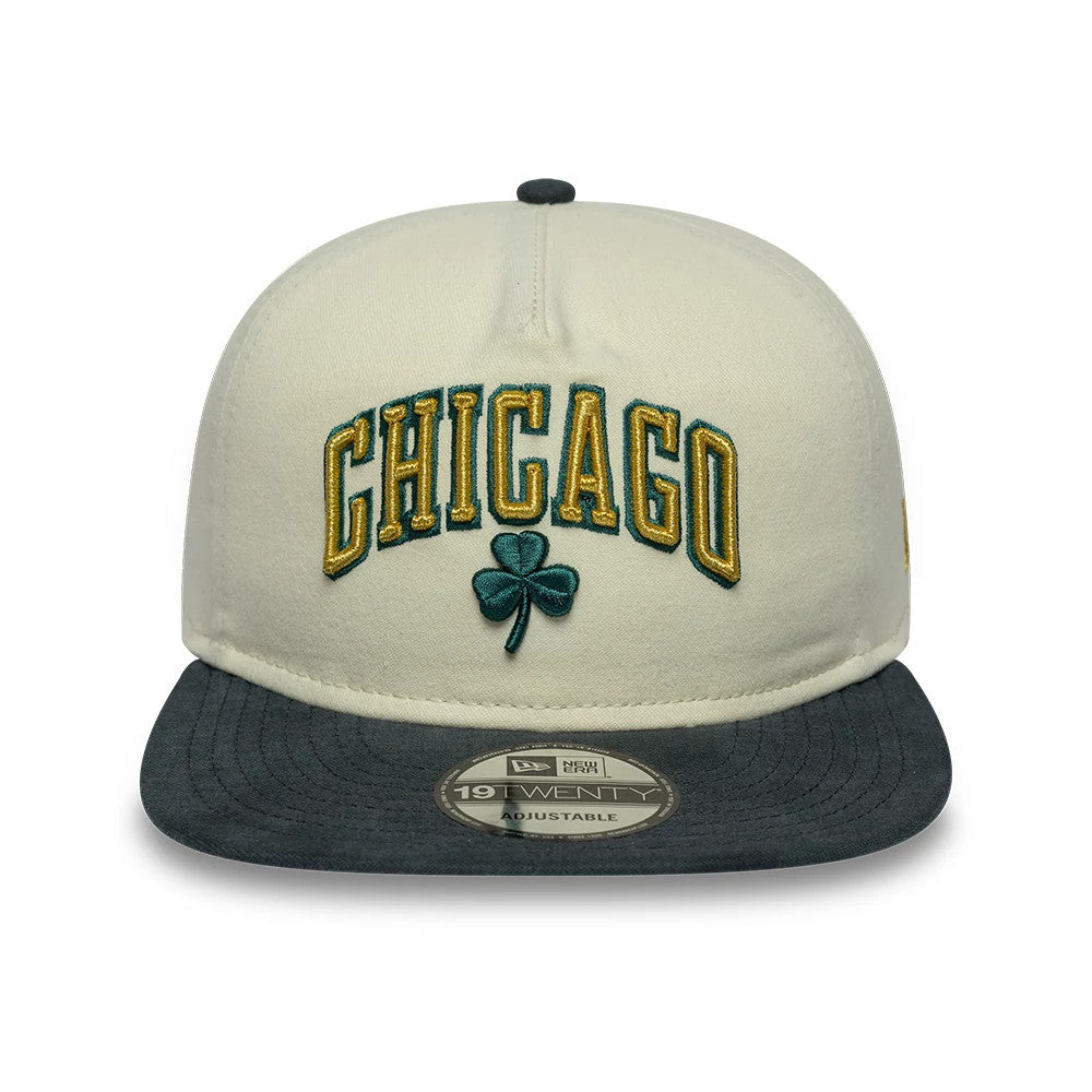Chicago Bulls NBA Metallic Logo Cream New Era 19TWENTY Adjustable Cap, front view showing raised gold and green embroidered CHICAGO text with a green shamrock on the cream crown, complemented by a dark grey visor featuring a 19TWENTY size sticker.