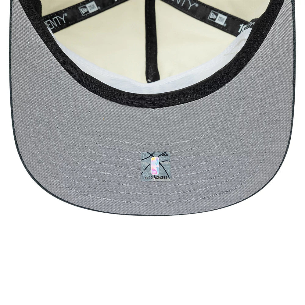 Boston Celtics NBA Metallic Logo Cream New Era 19TWENTY Adjustable Cap, inside view showing a cream sweatband, black taping with clear branding, and a grey undervisor with an NBA sticker placed centrally near the edge.