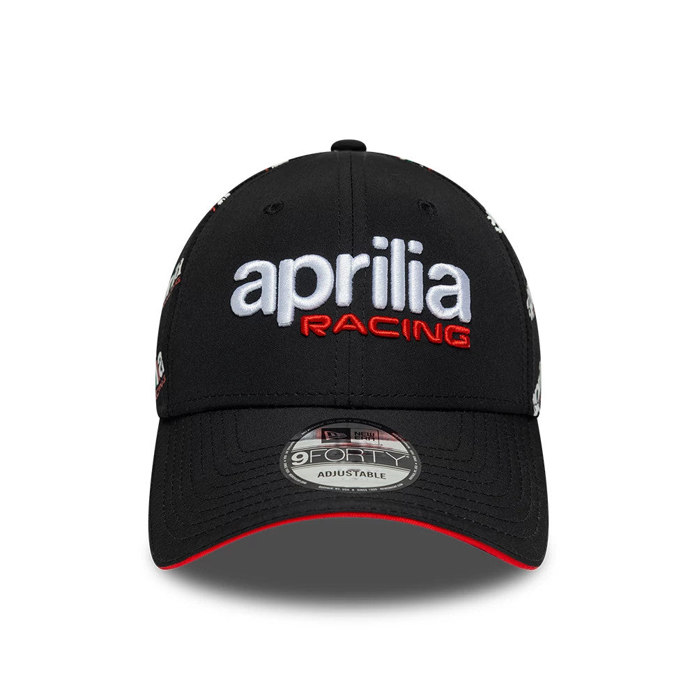 Aprilia All Over Print Black New Era 9FORTY Adjustable Cap, front view showing the white aprilia and red RACING embroidered lettering on the structured black crown, with an official 9FORTY size sticker on the black curved visor.