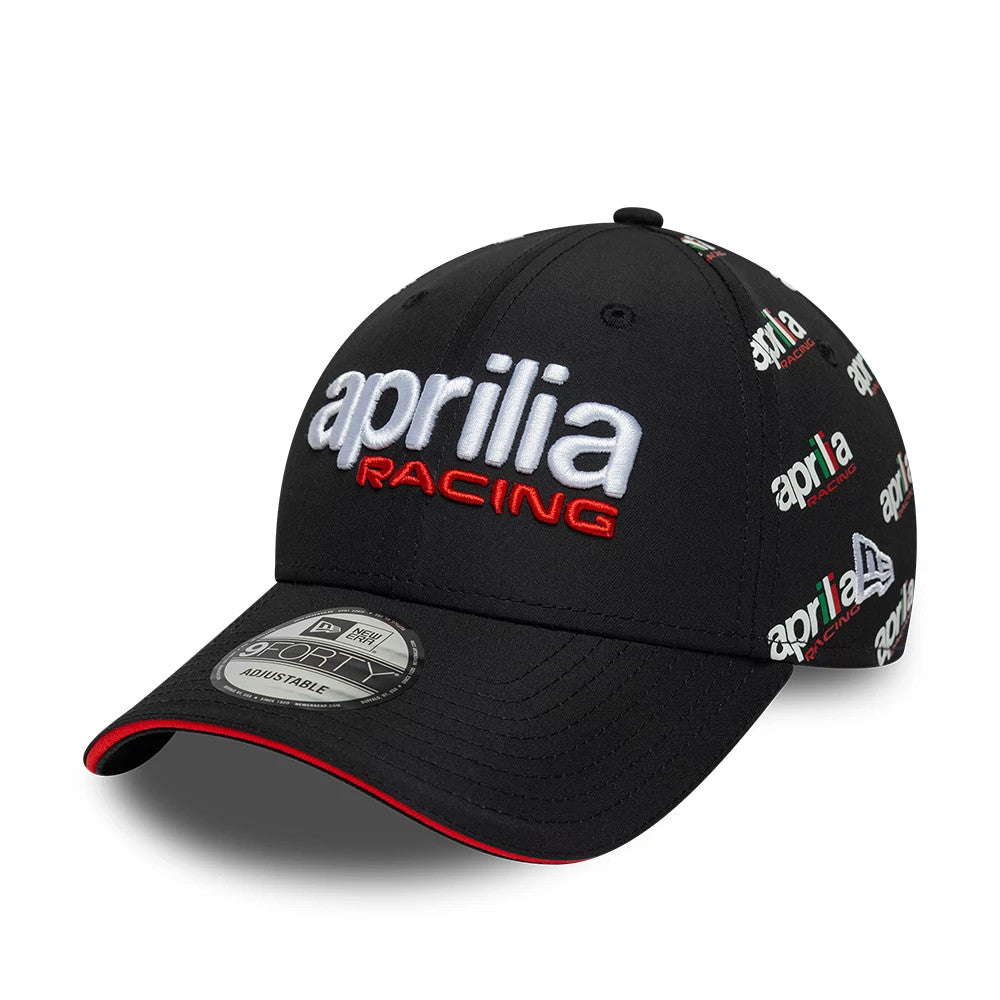 Aprilia All Over Print Black New Era 9FORTY Adjustable Cap, three-quarter view showing the white and red embroidered Aprilia Racing logo on the front panel, a series of small logos on the black crown, and a 9FORTY size sticker on the curved visor.