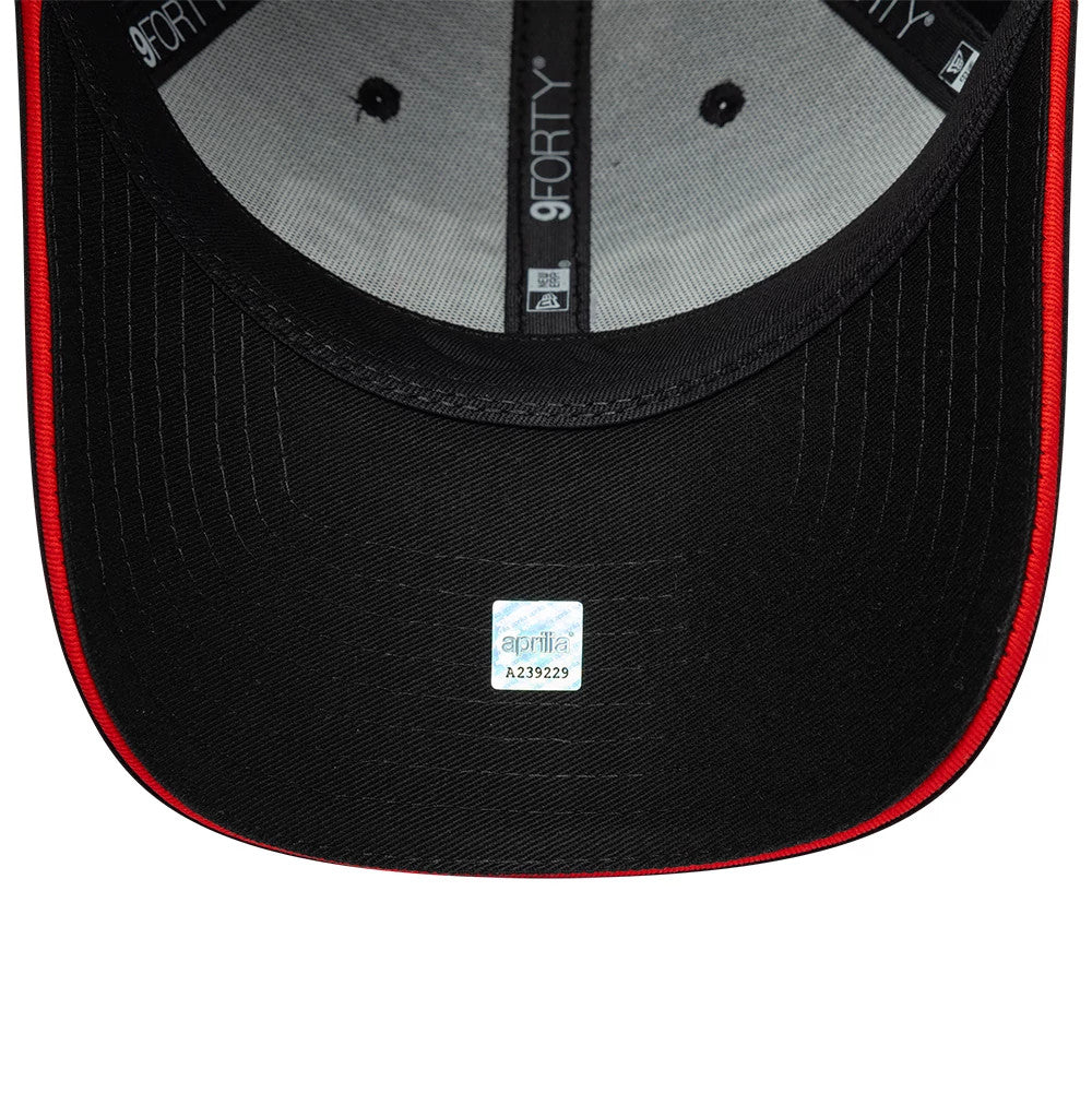Aprilia All Over Print Black New Era 9FORTY Adjustable Cap, inside view showing a light grey sweatband, a black undervisor with a distinctive red edge, and a small white sticker featuring branding at the centre.