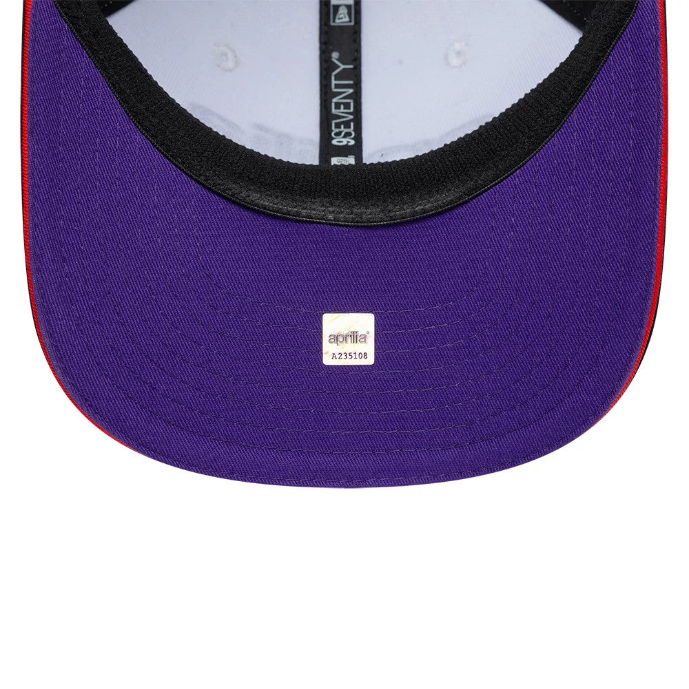 Aprilia Team White New Era 9SEVENTY Stretch Snap Adjustable Cap, inside view showing a purple undervisor with a central aprilia logo sticker, black sweatband and contrasting red stitching along the edges, beneath branded taping.