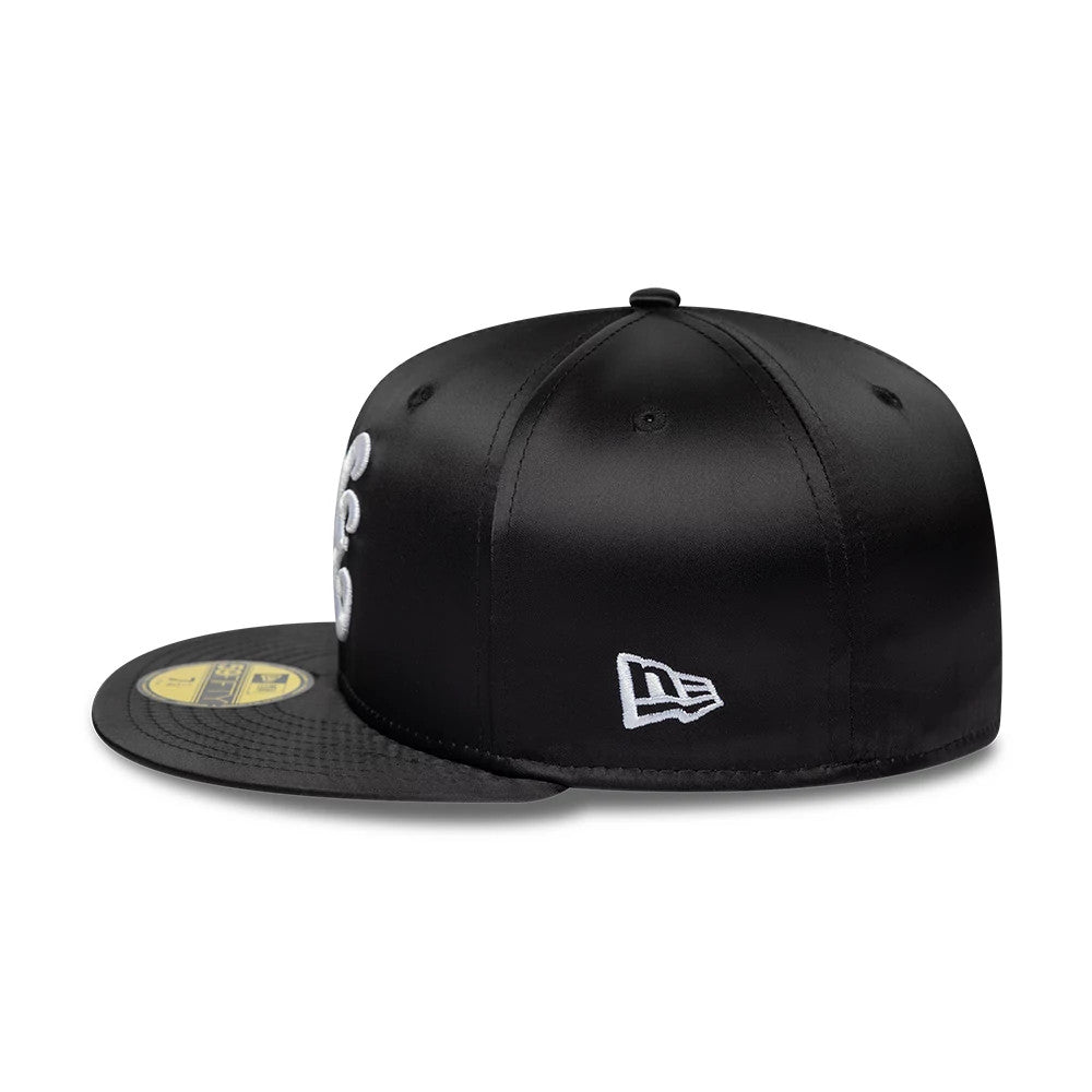 New Era Satin Black 59FIFTY Fitted Cap, side view showing the white embroidered New Era flag logo on the left side, black satin finish on the structured crown, and gold 59FIFTY size sticker on the black flat visor.
