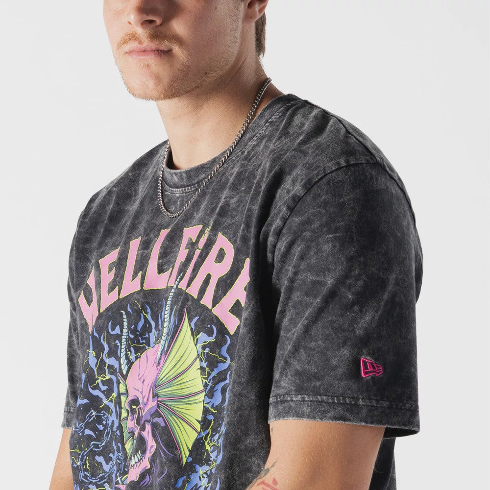 New Era Netflix Stranger Things Hell Fire Club Black T-Shirt, front view on-model showing a graphic of a pink skull with yellow horns and purple flames on the chest, large pink Hellfire lettering above.