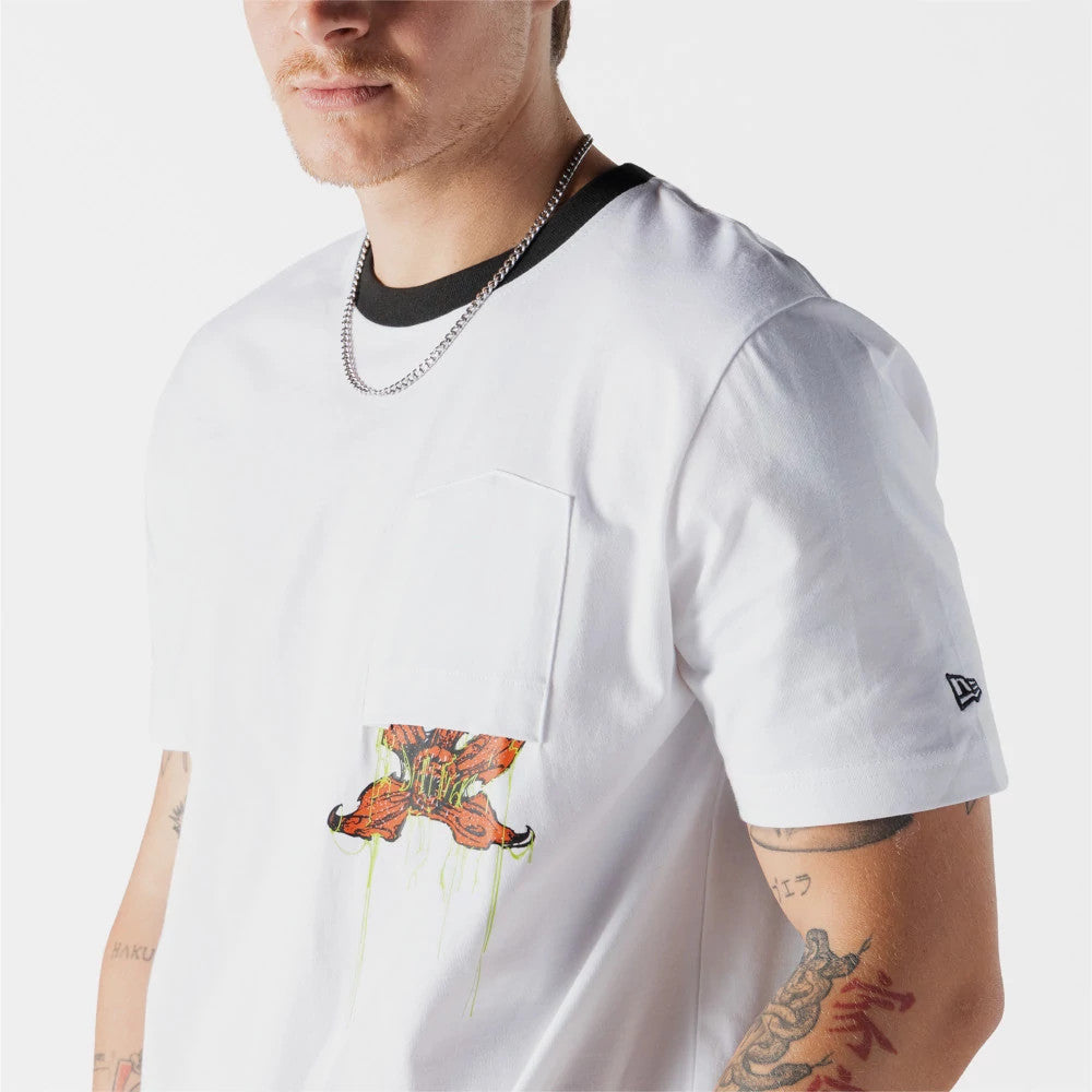 New Era Netflix Stranger Things Demogorgon White T-Shirt, three-quarter view on a model showcasing a detailed Demogorgon graphic emerging from the front pocket, black neckline trim, and an embroidered New Era logo on the left sleeve.
