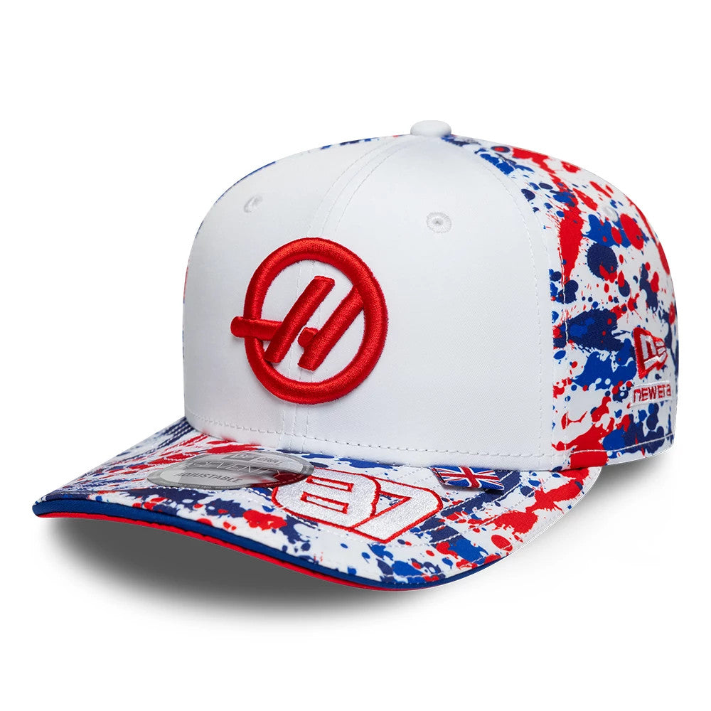 TGR Haas F1 Oliver Bearman Silverstone Race Special White New Era 9SEVENTY Stretch Snap Cap, three-quarter view showing a large red embroidered Haas logo on the front panel, a multicolour splatter pattern on the visor.