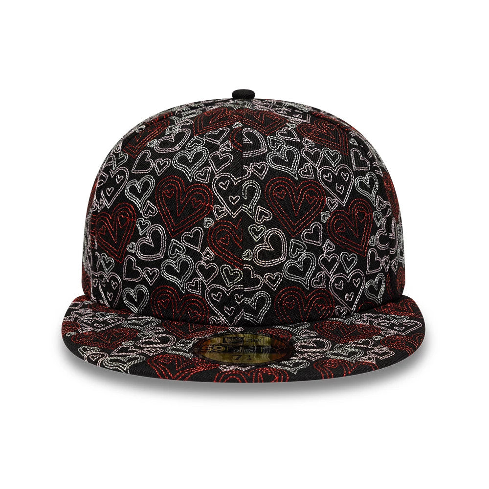 New Era All Over Hearts Black 59FIFTY Fitted Cap, front view showing intricate red and white embroidered heart patterns covering the entire structured crown and flat visor, with the gold 59FIFTY size sticker on top of the visor.