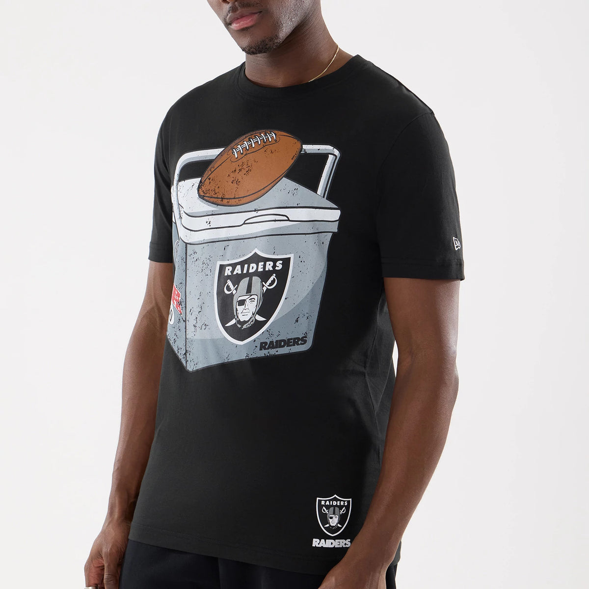 New Era Las Vegas Raiders NFL Training 2026 Black T-Shirt, front view on a model showing a large printed graphic of a cooler with a football on top, featuring the Raiders logo, and a small embroidered Raiders logo near the hem.