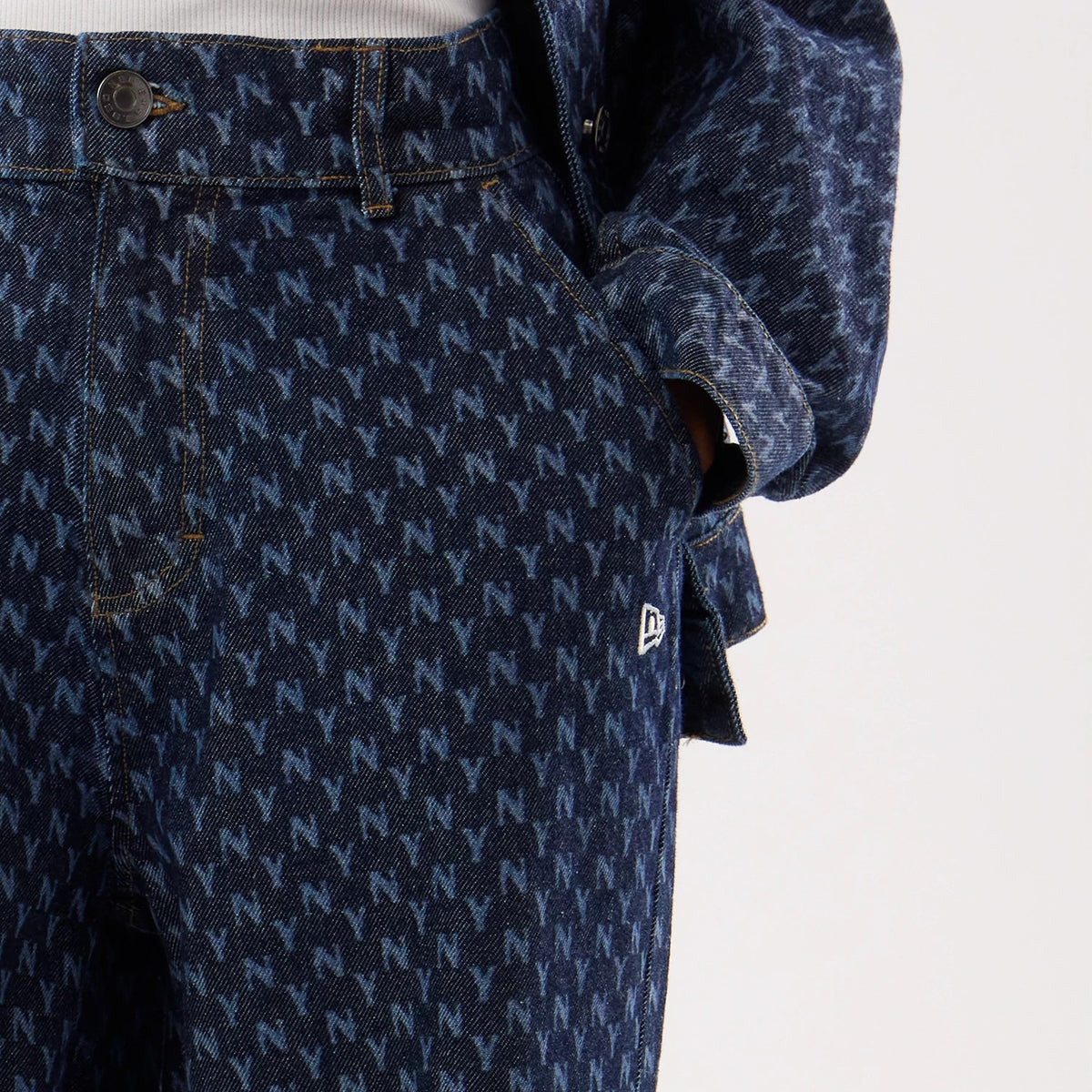 New Era New York Yankees Womens MLB Denim Navy Wide Leg Trousers, three-quarter view showing the all-over monogrammed NY pattern in light blue on dark denim, with a New Era flag logo on the pocket and traditional button closure.