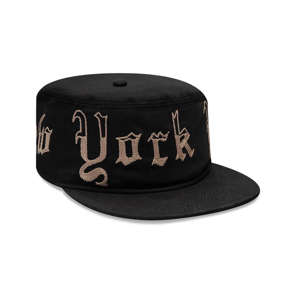 New Era New York Yankees MLB Heritage Black Pillbox Cap, front view showing the Old English style New York lettering in tan embroidery across the structured black crown, with a flat black visor and matching black top button.