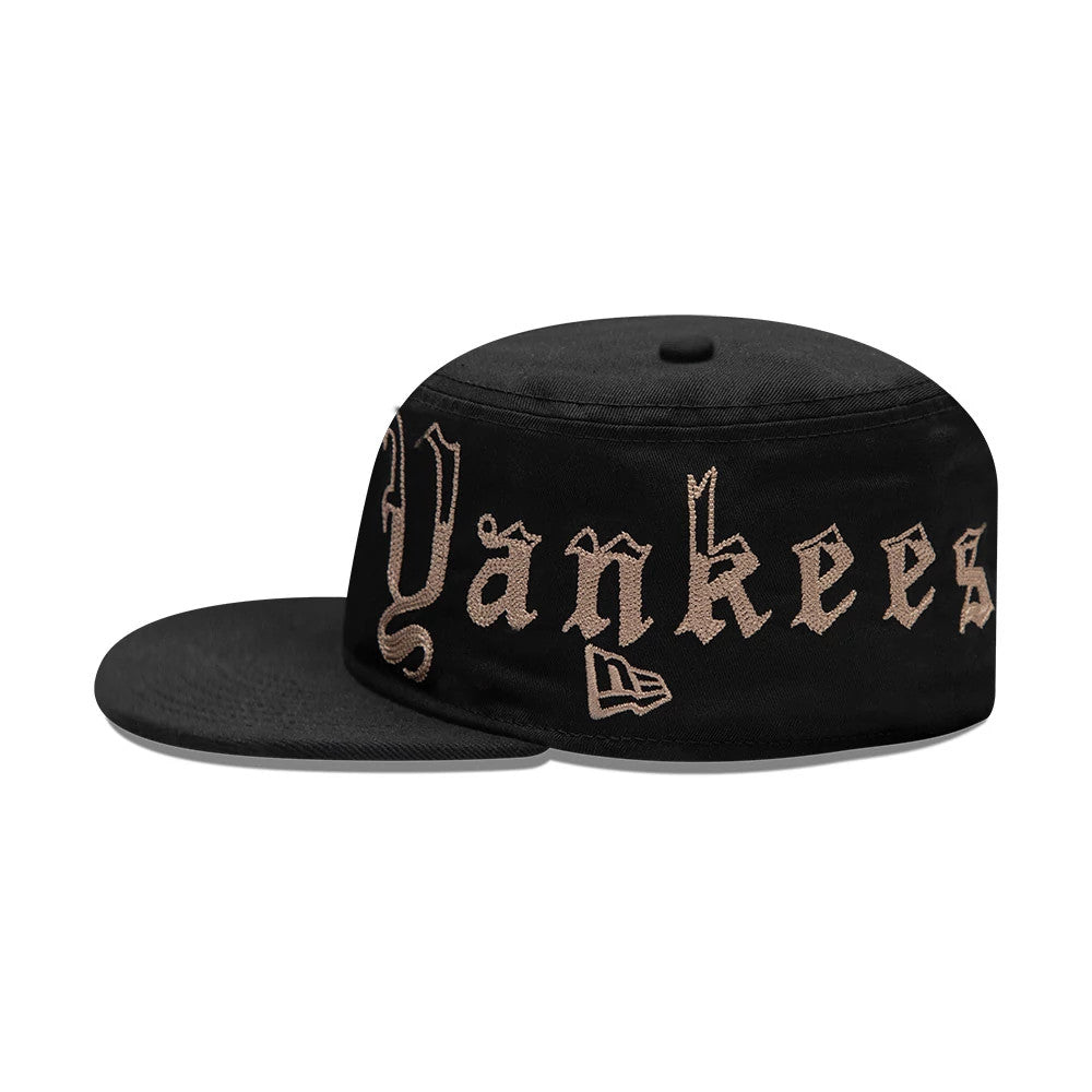 New Era New York Yankees MLB Heritage Black Pillbox Cap, side view showing tan Yankees script embroidery across the front panel, a matching New Era flag logo on the left, and a flat black visor extending outward.