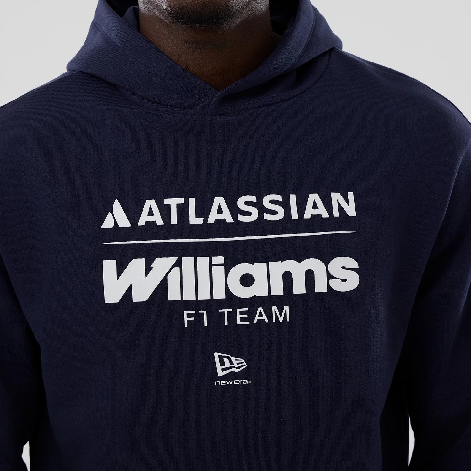 New Era Williams Navy Oversized Pullover Hoodie, front view showing white printed Atlassian and Williams F1 Team logos across the chest, a classic New Era logo printed beneath them, and the edge of the navy hood at the top.