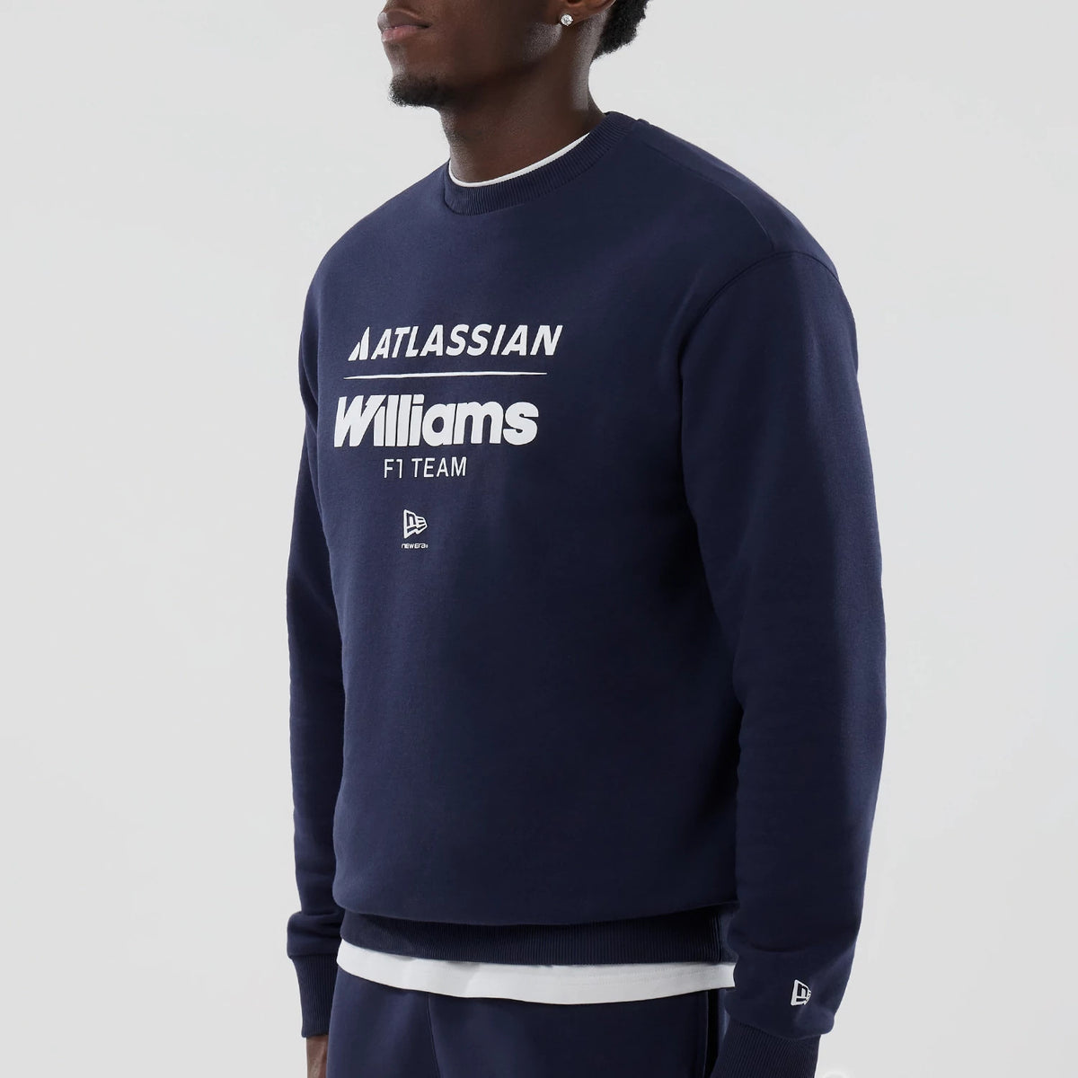 New Era Williams Navy Oversized Crewneck Sweater, on-model view showing the front with white Atlassian and Williams F1 Team lettering, New Era flag logo below, with ribbed cuffs and an additional logo on the left sleeve.