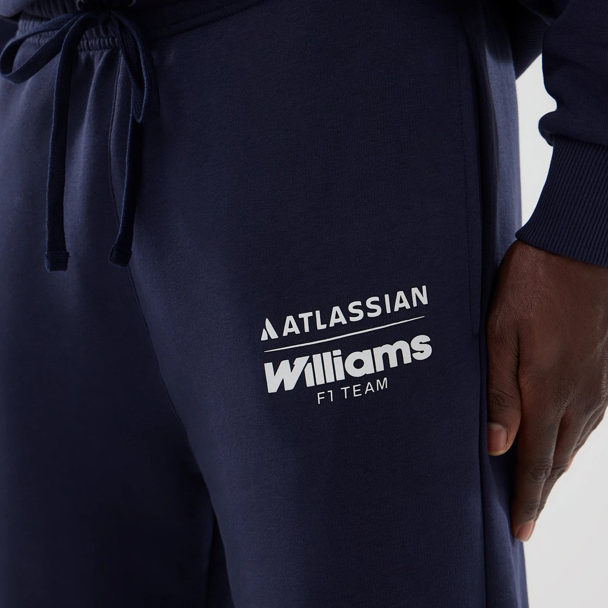 New Era Williams Navy Joggers, front view on a model showing the prominent white Williams F1 Team and Atlassian logos on the upper right leg, with drawstrings at the elasticated waistband and a soft ribbed cuff at the ankle.