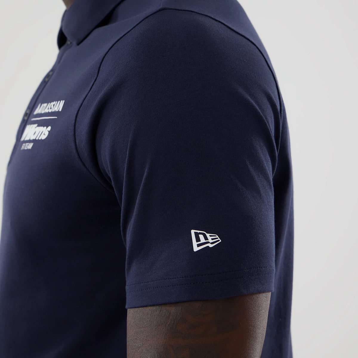 New Era Williams Navy Polo T-Shirt, side view showing the New Era embroidered logo on the sleeve, contrasting with the deep navy fabric, and front text reading ACKSON M. orms on the chest.