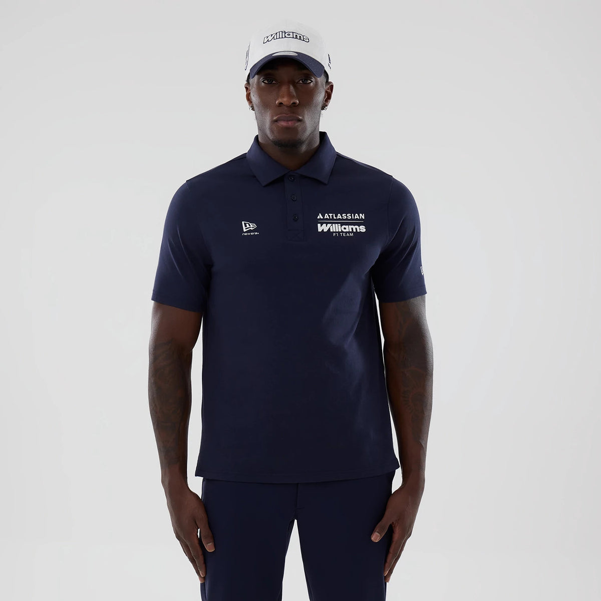 New Era Williams Navy Polo T-Shirt, front view on-model displaying a navy blue design with a short collar and buttoned placket, featuring a white embroidered New Era logo on the chest, and white Williams lettering on the right side.