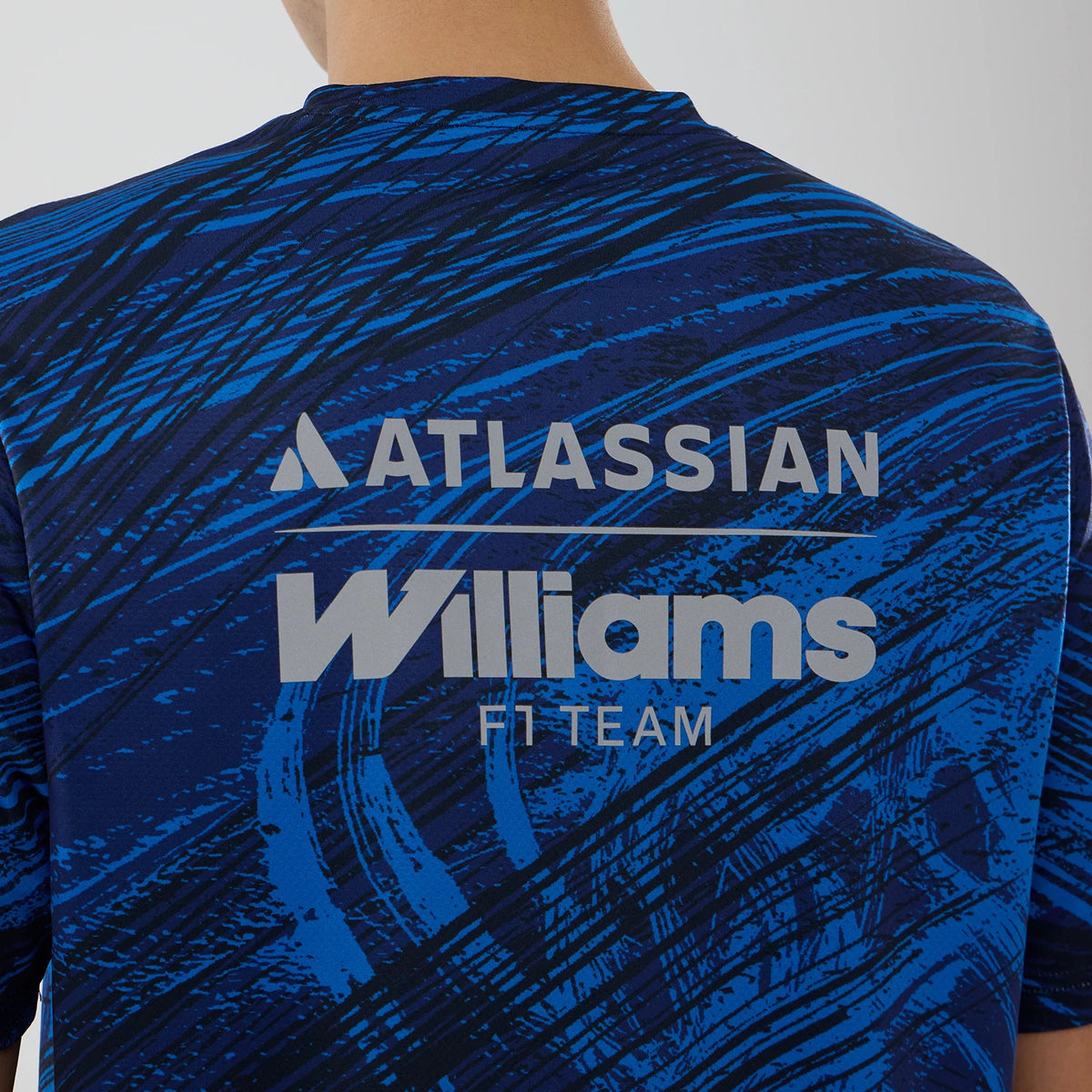 New Era Williams Navy Active T-Shirt, back view showing a navy pattern with blue brushstrokes, printed Atlassian logo across the upper back, and Williams F1 Team lettering prominently featured below in contrasting white.