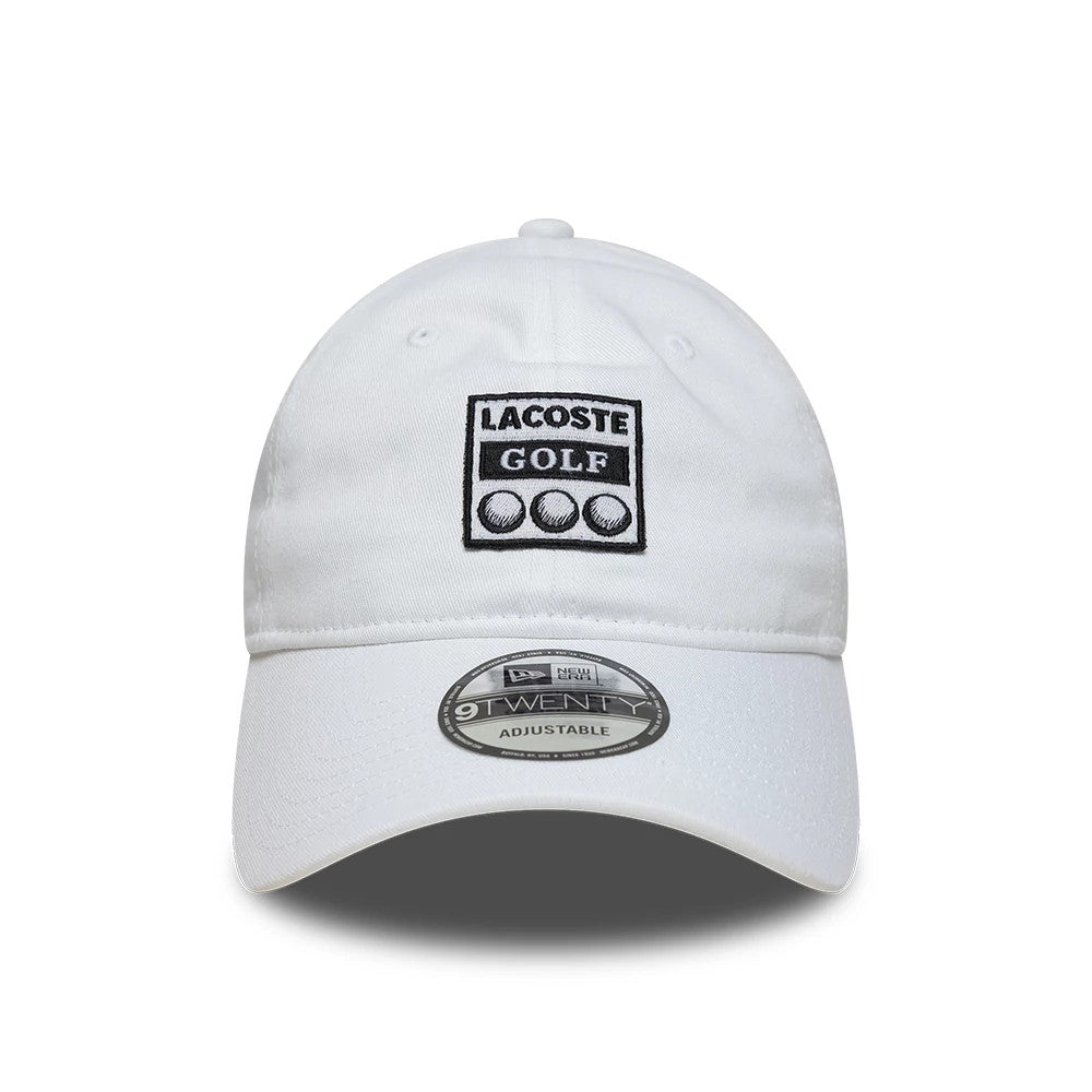Lacoste X New Era Golf White New Era 9TWENTY Adjustable Cap, front view showing the black and white embroidered Lacoste Golf logo on the unstructured white crown, with a curved white visor and a 9TWENTY size sticker on the top.