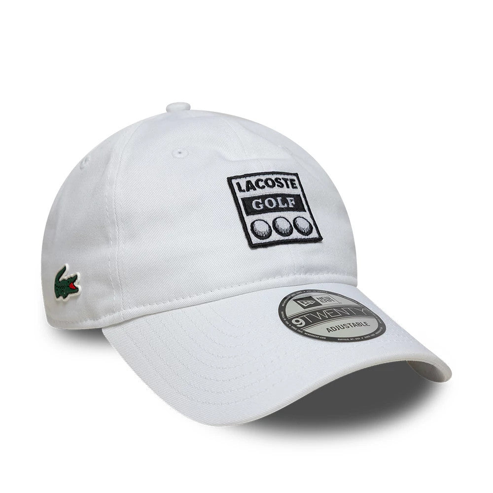 Lacoste X New Era Golf White New Era 9TWENTY Adjustable Cap, three-quarter view showing the black embroidered Lacoste Golf logo on the front panel, the green crocodile logo on the left side, and the 9TWENTY size sticker on the curved visor.