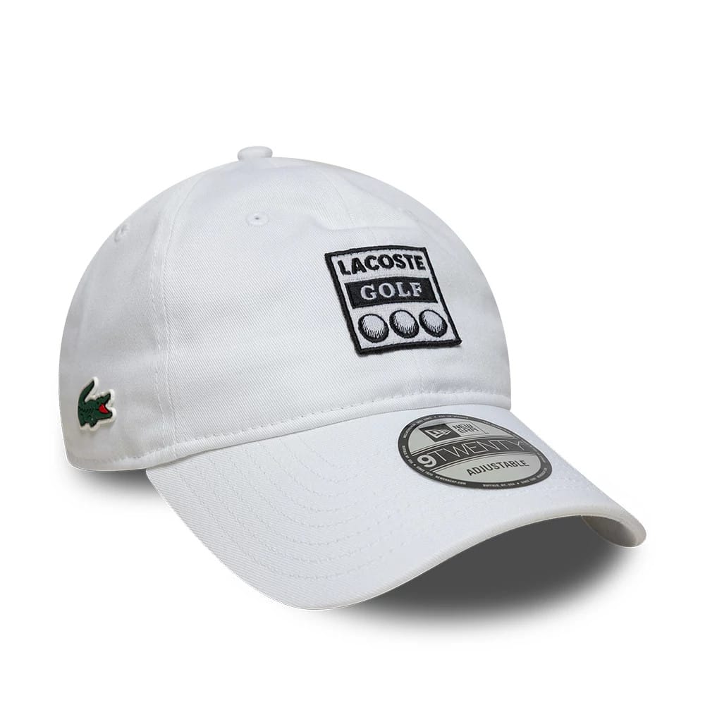 Lacoste X New Era Golf White New Era 9TWENTY Adjustable Cap, three-quarter view showing the black embroidered Lacoste Golf logo on the front panel, the green crocodile logo on the left side, and the 9TWENTY size sticker on the curved visor.