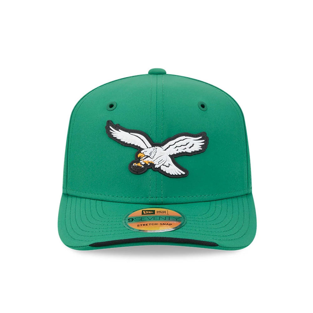 Eagles NFL Sideline 2026 Green New Era 9SEVENTY Stretch Snap Adjustable Cap, front view showing a raised embroidered eagle logo on the structured green crown, with black eyelets and a gold 9SEVENTY size sticker on the green curved visor.