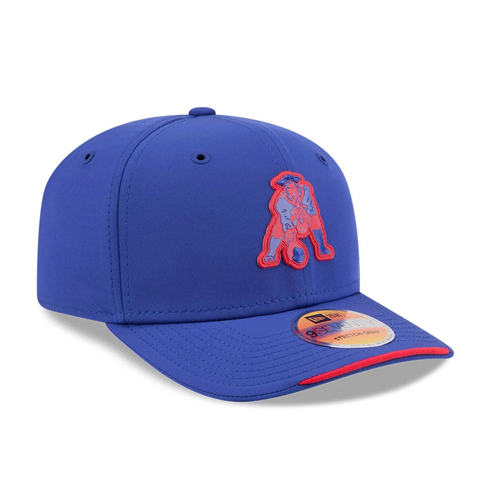 Patriots NFL Sideline 2026 Blue New Era 9SEVENTY Stretch Snap Adjustable Cap, three-quarter view showing the front panel with a red-outlined patriot logo, blue curved visor with a contrasting red tip, and the 9SEVENTY size sticker on top.