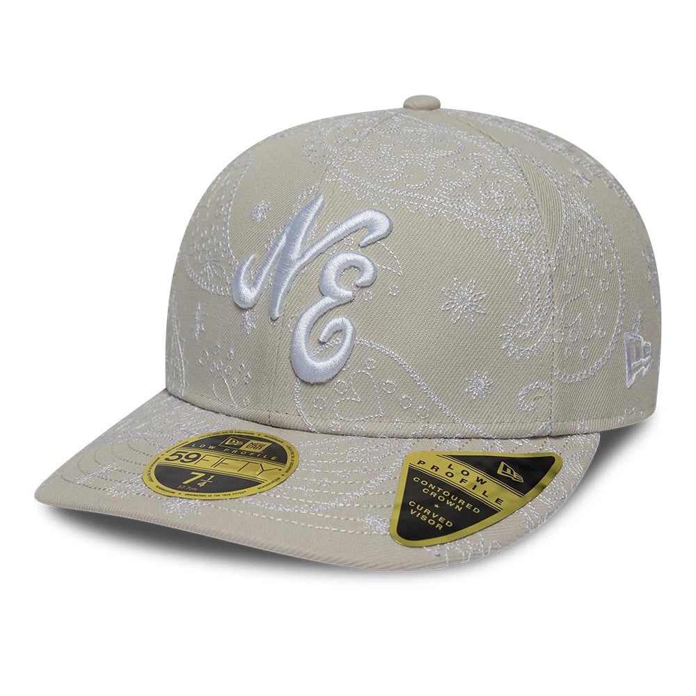 New Era All Over Paisley Cream Low Profile 59FIFTY Fitted Cap, three-quarter view showing the white embroidered NE logo on the front panel, intricate paisley pattern across cream fabric, and gold 59FIFTY size sticker on the curved visor.