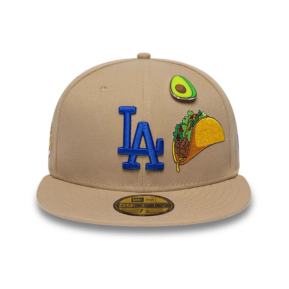 LA Dodgers MLB Food Beige New Era 59FIFTY Fitted Cap, front view showing the blue embroidered LA logo on the centre front panel, with an avocado and a taco graphic on the right side and a gold 59FIFTY size sticker on the visor.