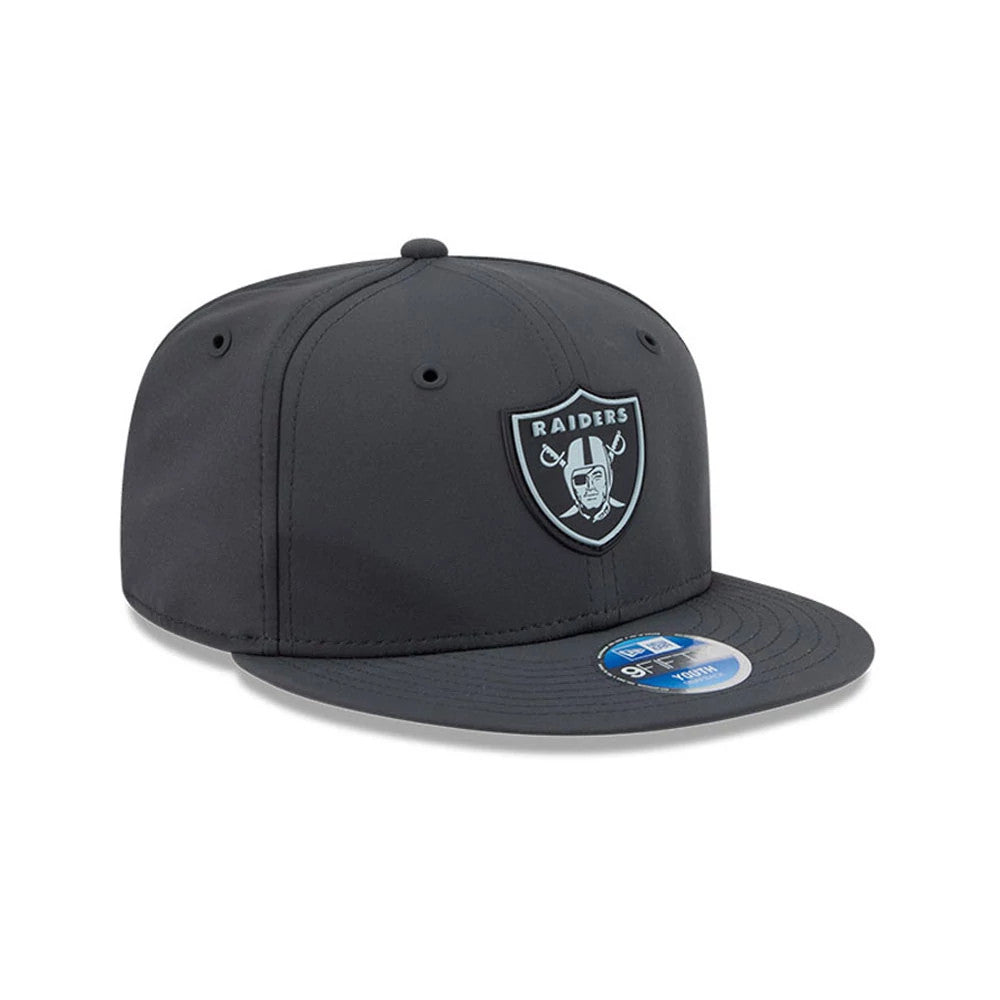 Raiders Youth NFL Sideline 2026 Charcoal New Era 9FIFTY Snapback Adjustable Cap, three-quarter view showing a raised embroidered Raiders logo on the front panel, flat charcoal visor with a 9FIFTY size sticker, and a structured crown.