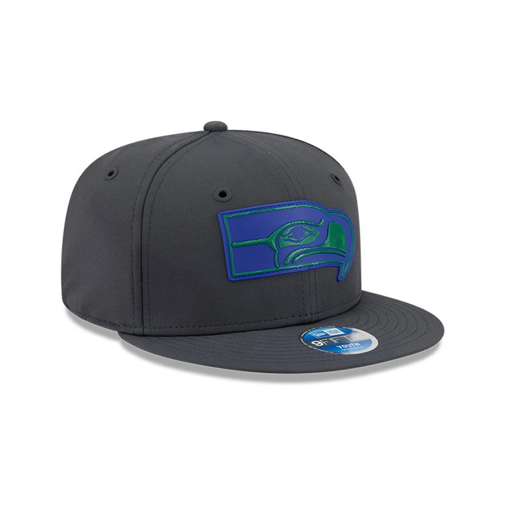 Seahawks Youth NFL Sideline 2026 Charcoal New Era 9FIFTY Snapback Adjustable Cap, three-quarter view showing the green and blue embroidered Seahawks logo on the front panels, with a flat charcoal visor and a 9FIFTY size sticker in place.