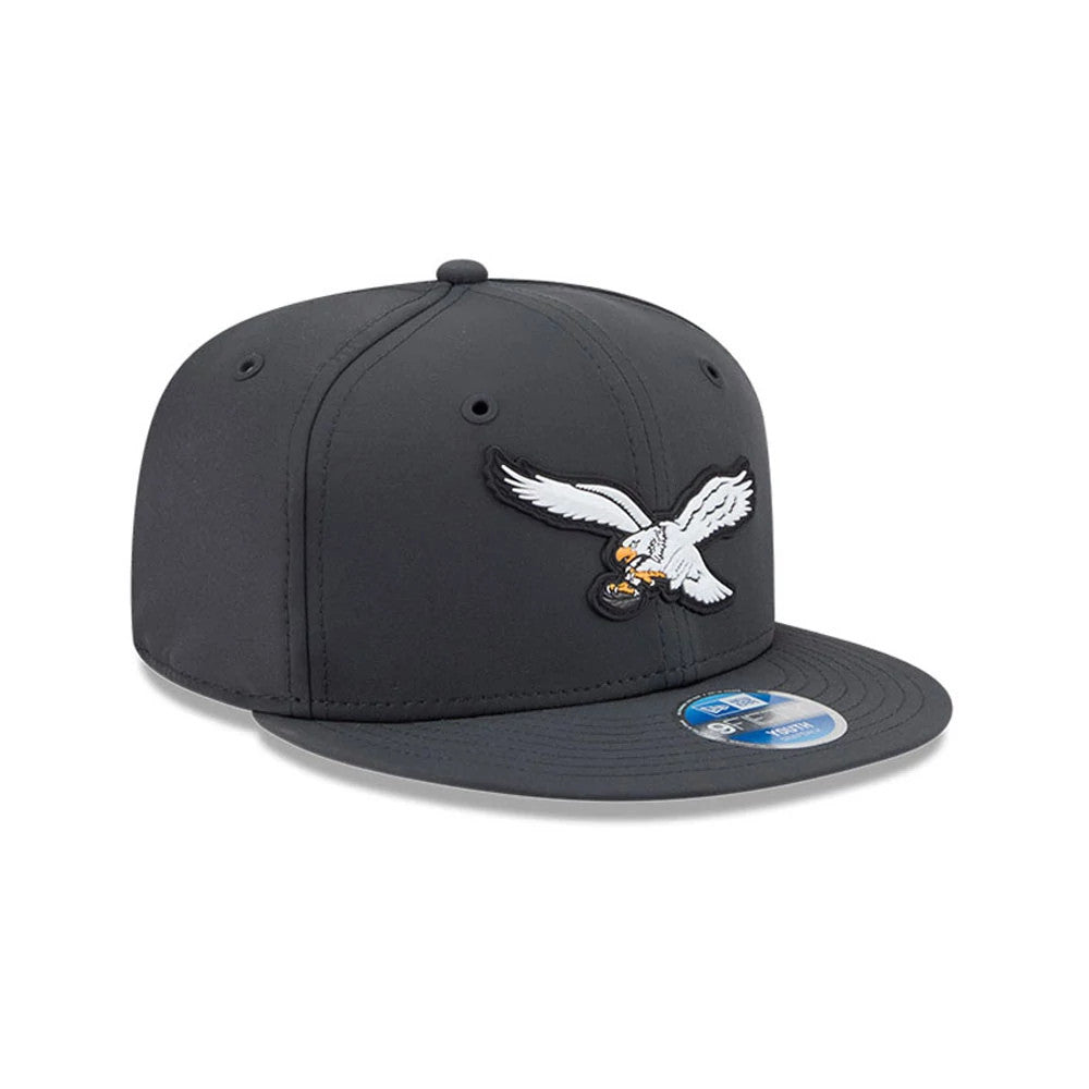 Eagles Youth NFL Sideline 2026 Charcoal New Era 9FIFTY Snapback Adjustable Cap, three-quarter view showing the raised white and grey embroidered eagle logo on the front panel, flat charcoal visor, and 9FIFTY size sticker on the top.