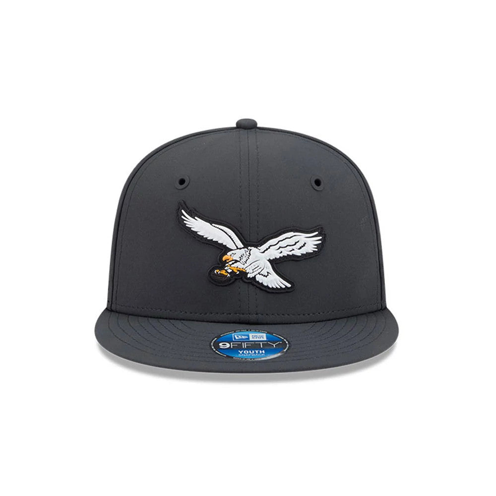 Eagles Youth NFL Sideline 2026 Charcoal New Era 9FIFTY Snapback Adjustable Cap, front view showing a white embroidered eagle logo on the structured charcoal crown, a charcoal flat visor, and a blue 9FIFTY youth size sticker.