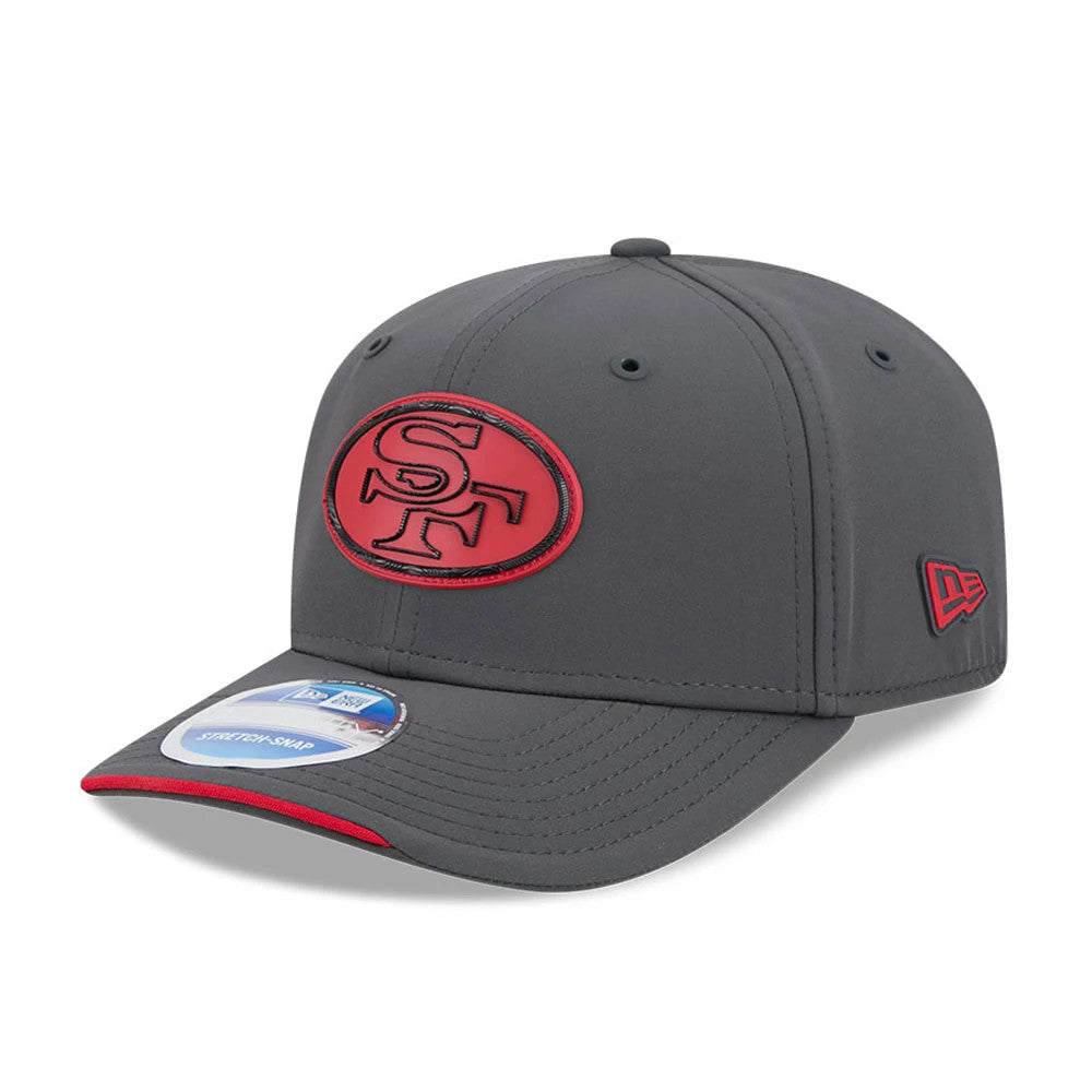 49ers NFL Sideline 2026 Charcoal New Era 9SEVENTY Stretch Snap Adjustable Cap, three-quarter view showing raised SF logo in red and black embroidery on the front panel, pre-curved visor with red undervisor.