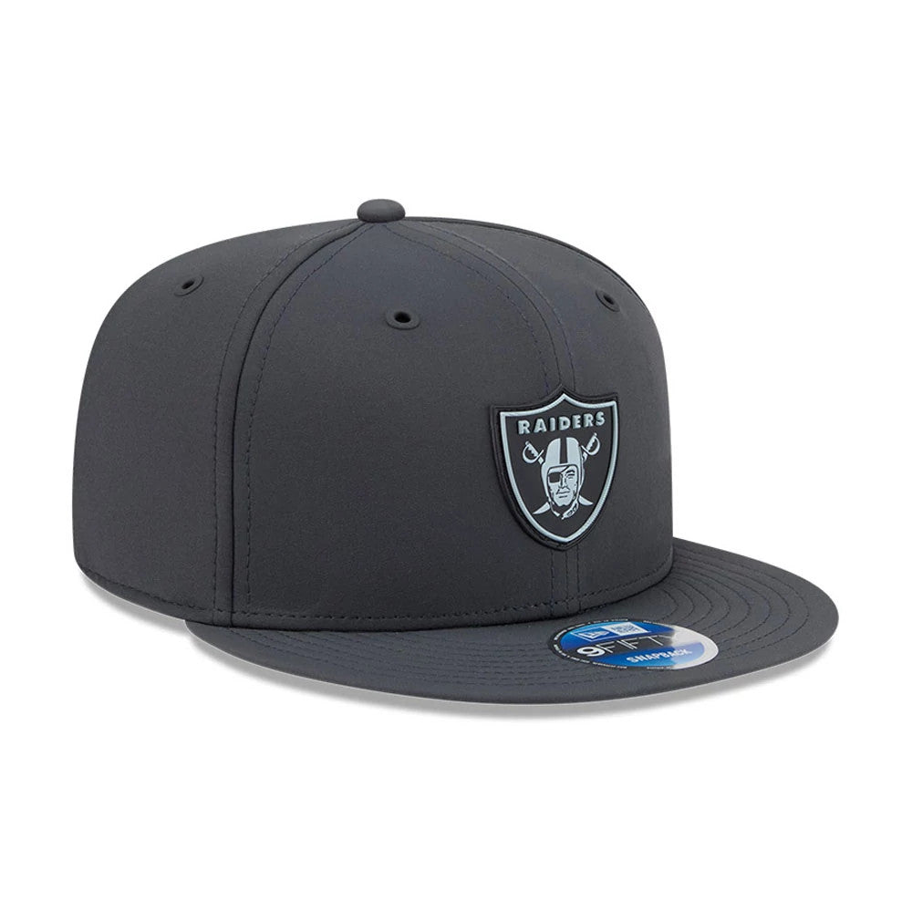 Raiders NFL Sideline 2026 Charcoal New Era 9FIFTY Snapback Adjustable Cap, front view showing the raised grey and black Raiders logo embroidered on the structured front panel, with a flat charcoal visor and a 9FIFTY size sticker on the visor.