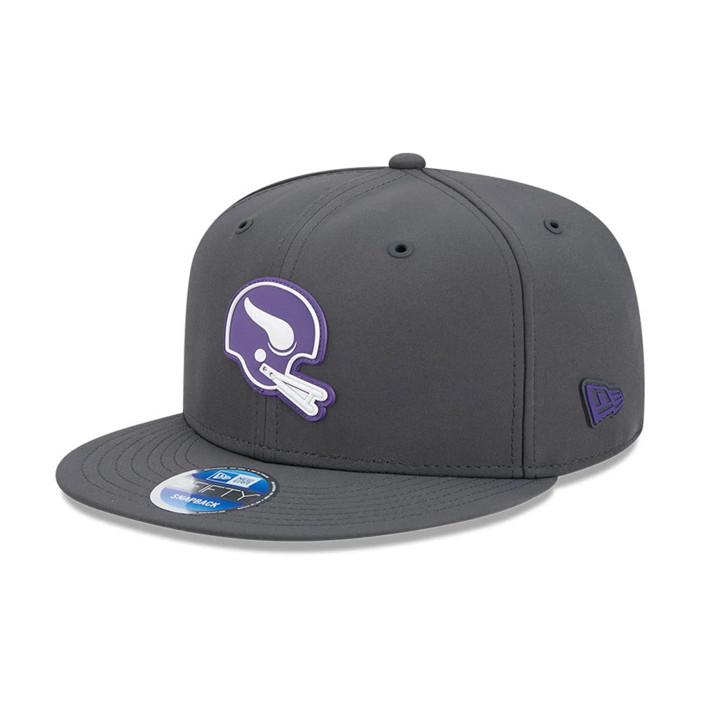 Vikings NFL Sideline 2026 Charcoal New Era 9FIFTY Snapback Adjustable Cap, front view showing a purple and white helmet graphic on the front panel, with a matching purple New Era flag logo on the left side and a 9FIFTY size sticker on the visor.