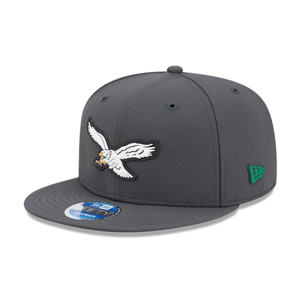 Eagles NFL Sideline 2026 Charcoal New Era 9FIFTY Snapback Adjustable Cap, front view showing the raised white eagle logo with outstretched wings on the front panel, a flat charcoal visor with a 9FIFTY size sticker.