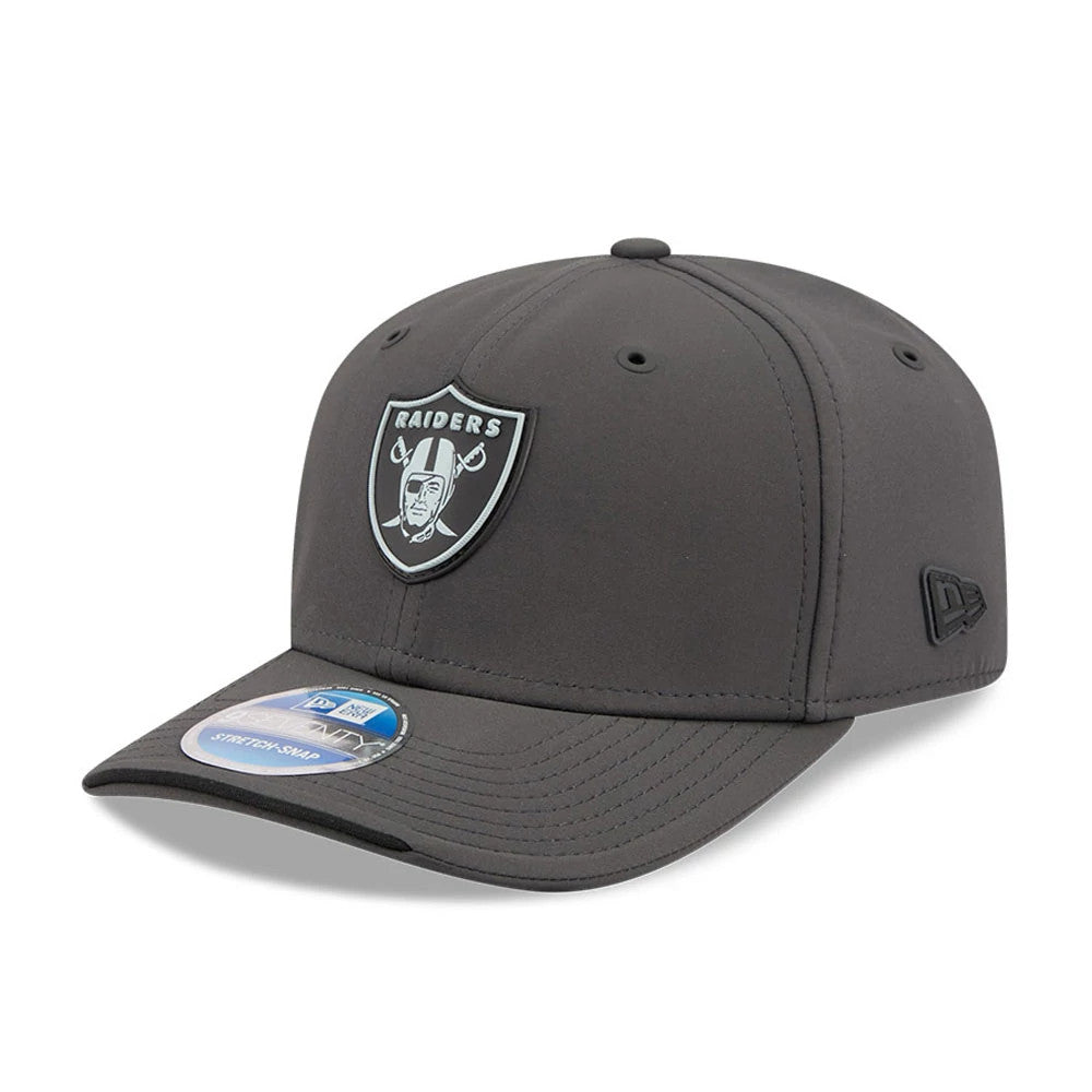 Raiders NFL Sideline 2026 Charcoal New Era 9SEVENTY Stretch Snap Adjustable Cap, three-quarter view showing the black and silver Raiders logo patch on the front panel, black embroidered New Era flag logo on the left side.