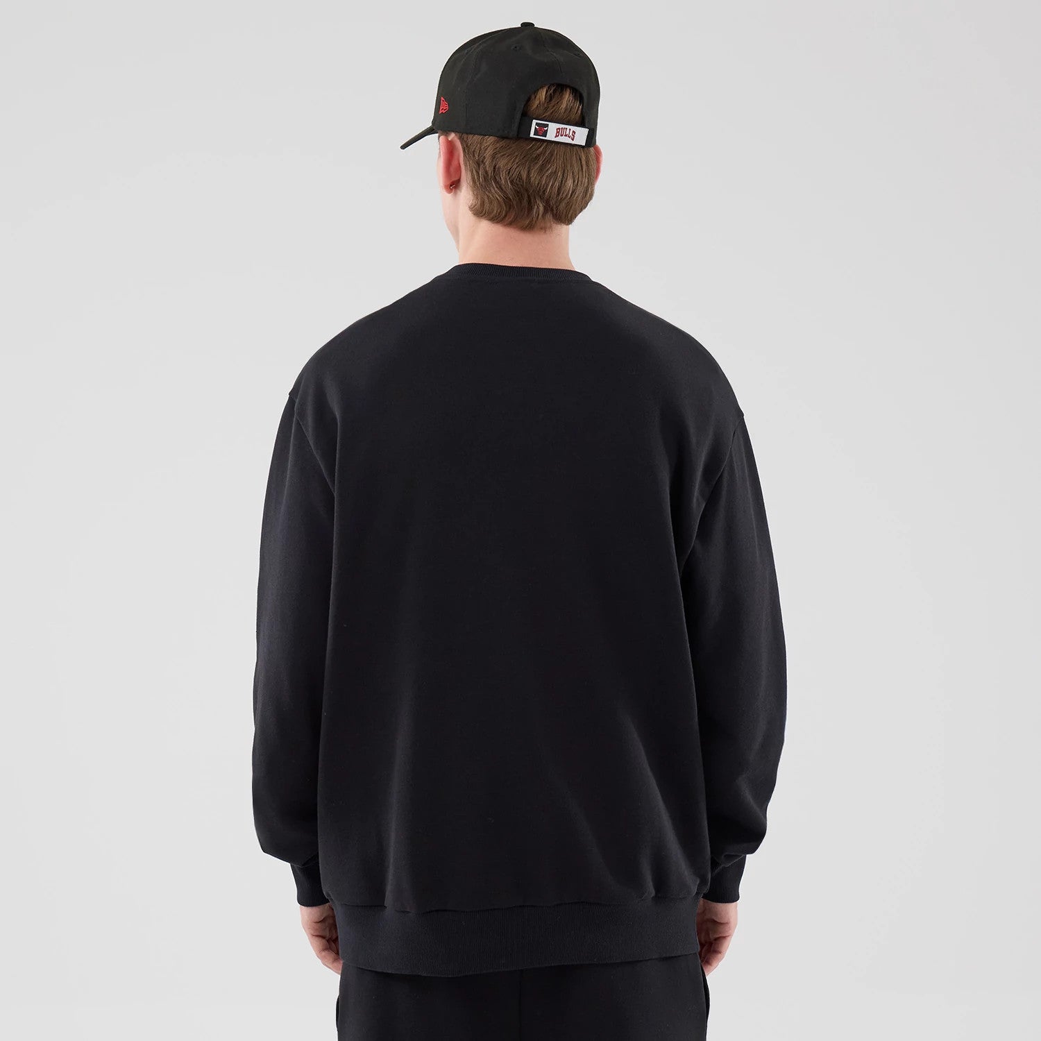 The model is wearing this NBA League Essential Chicago Bulls Oversized Crew Neck Sweater in black. 2
