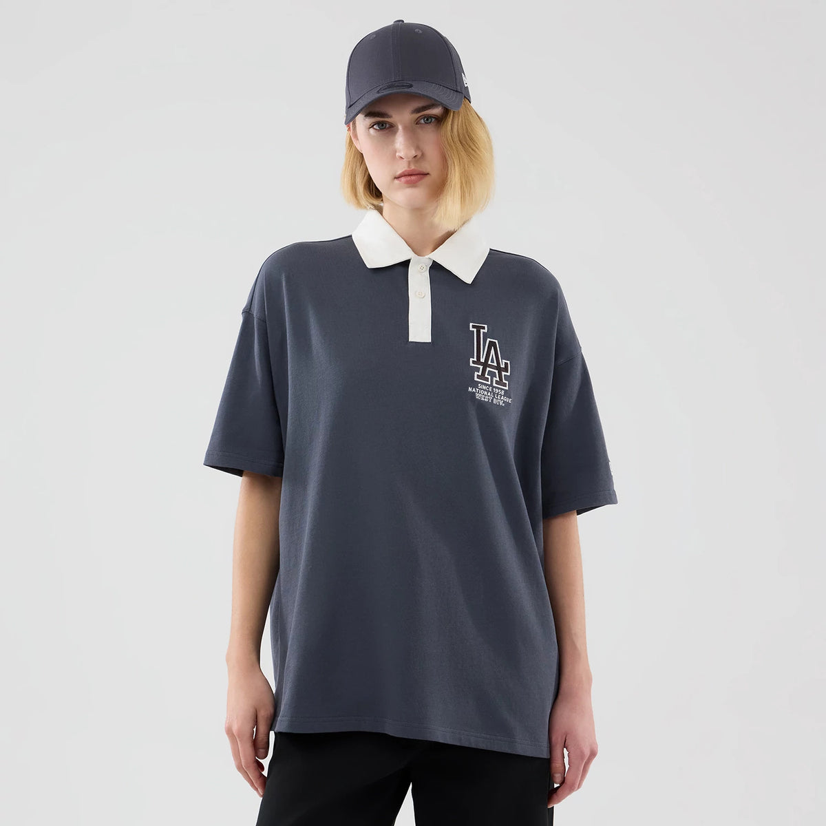 New Era LA Dodgers MLB Grey Polo T-Shirt, front view on a model showing the contrasting white collar and button placket, an embroidered LA Dodgers logo on the left chest, paired stylishly with a matching grey cap.