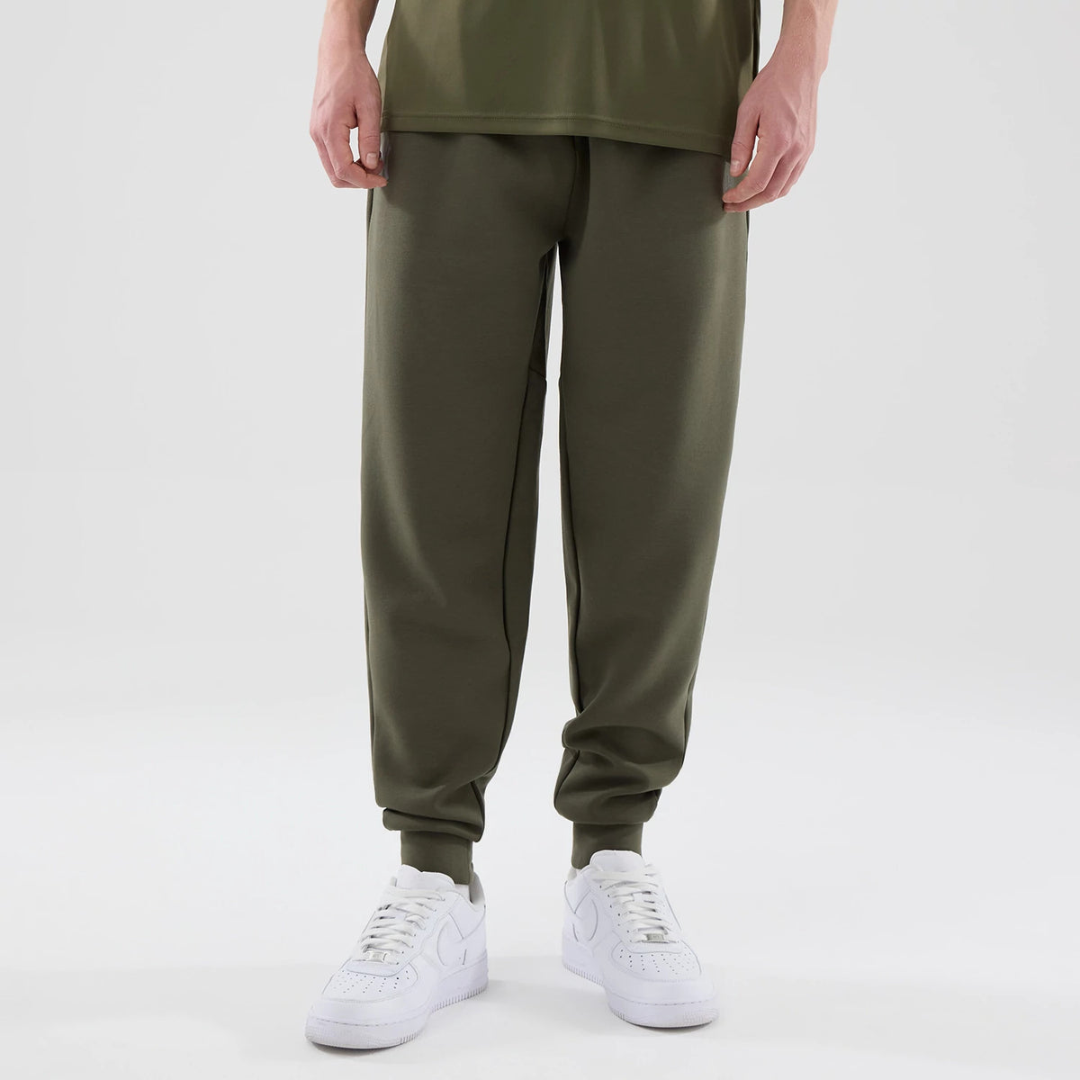 New Era New York Yankees MLB Core Plus Green Joggers, front view on a model with an olive green finish, featuring a relaxed fit that tapers down to ribbed cuffs, and paired with white sneakers on a plain background.