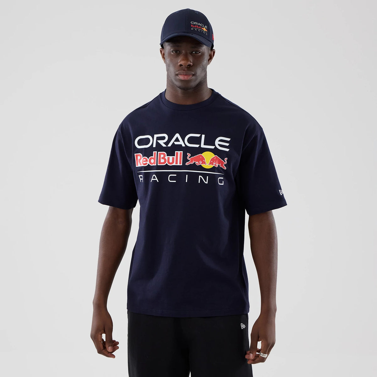 New Era Red Bull Racing Graphic Dark Blue Oversized T-Shirt, front view on-model showing large white Oracle lettering above the Red Bull logo and Racing text in front, with a small embroidered New Era logo on the sleeve.