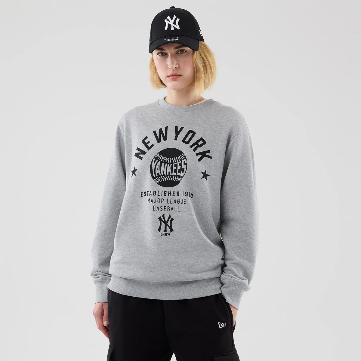 The model is wearing this MLB Graphic New York Yankees Oversized Crew Neck Sweater in grey. 4