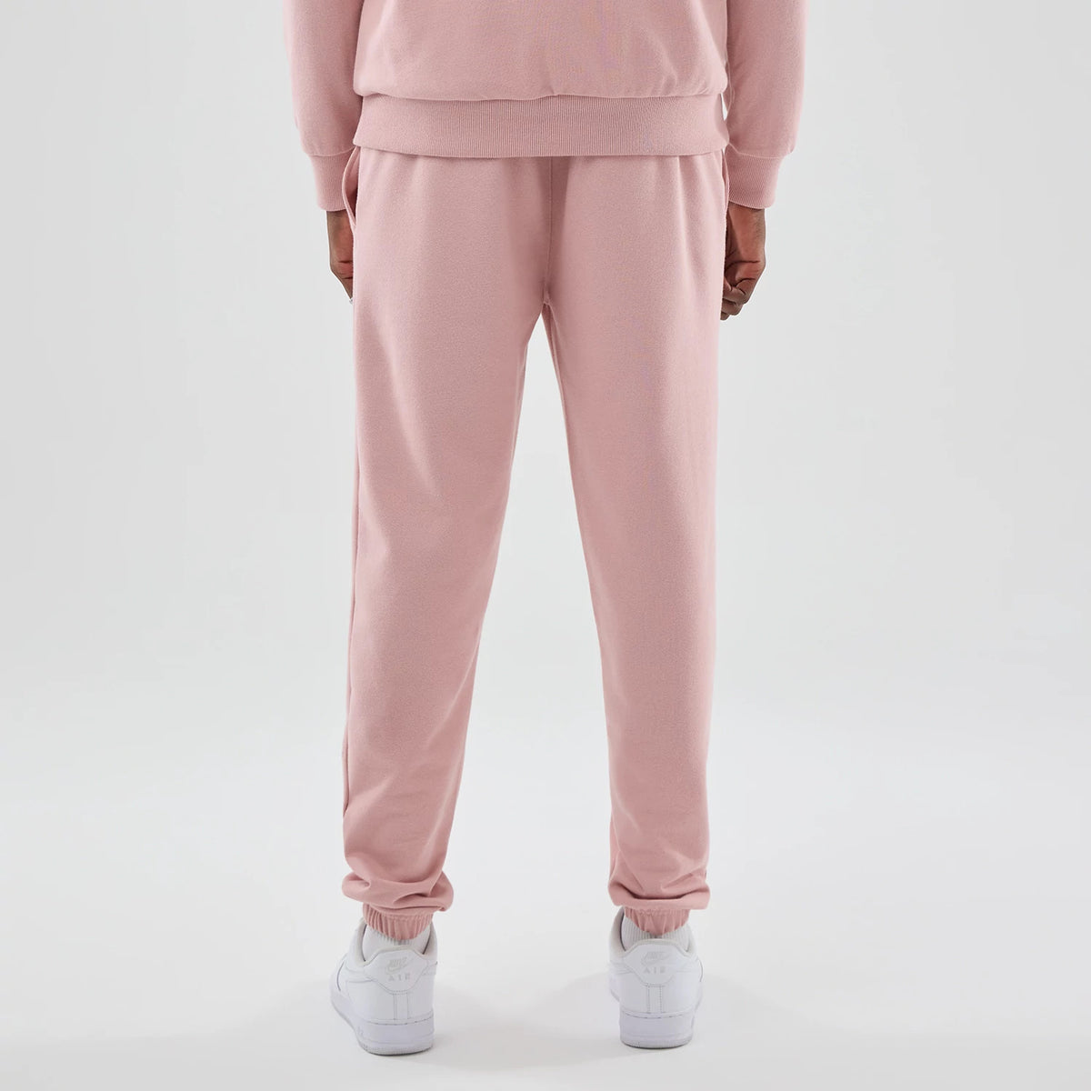 New Era LA Dodgers MLB Midi League Essential Pastel Pink Joggers, rear view on a model showing the elasticated cuffs and waistband, pastel pink colour, and relaxed fit, paired with white trainers for a casual look.