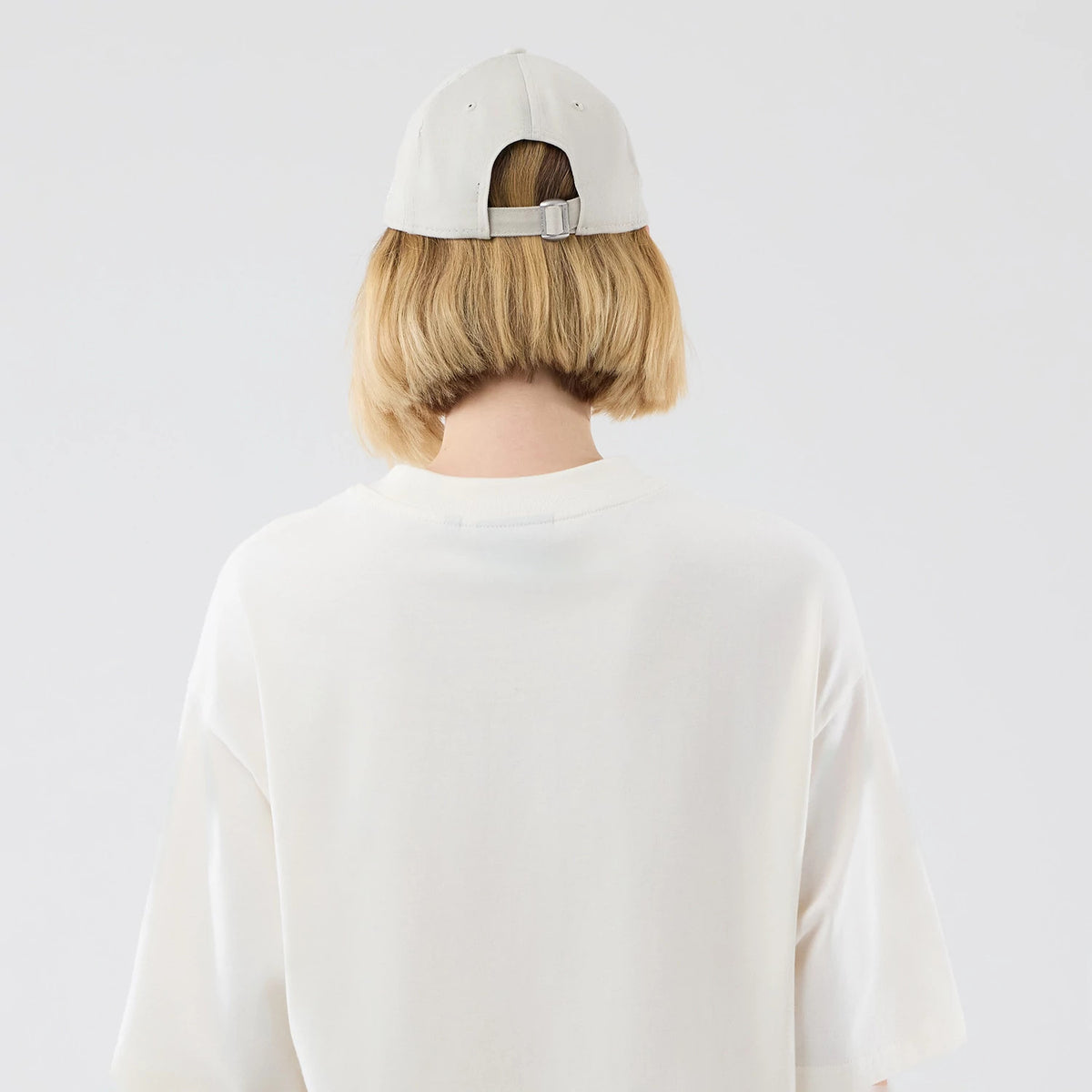 New Era New York Yankees MLB Arch Graphic Open White Oversized T-Shirt, back view on a model wearing a light-coloured cap, showing the plain oversized white fabric with short sleeves and a loose fit that drapes comfortably down the back.