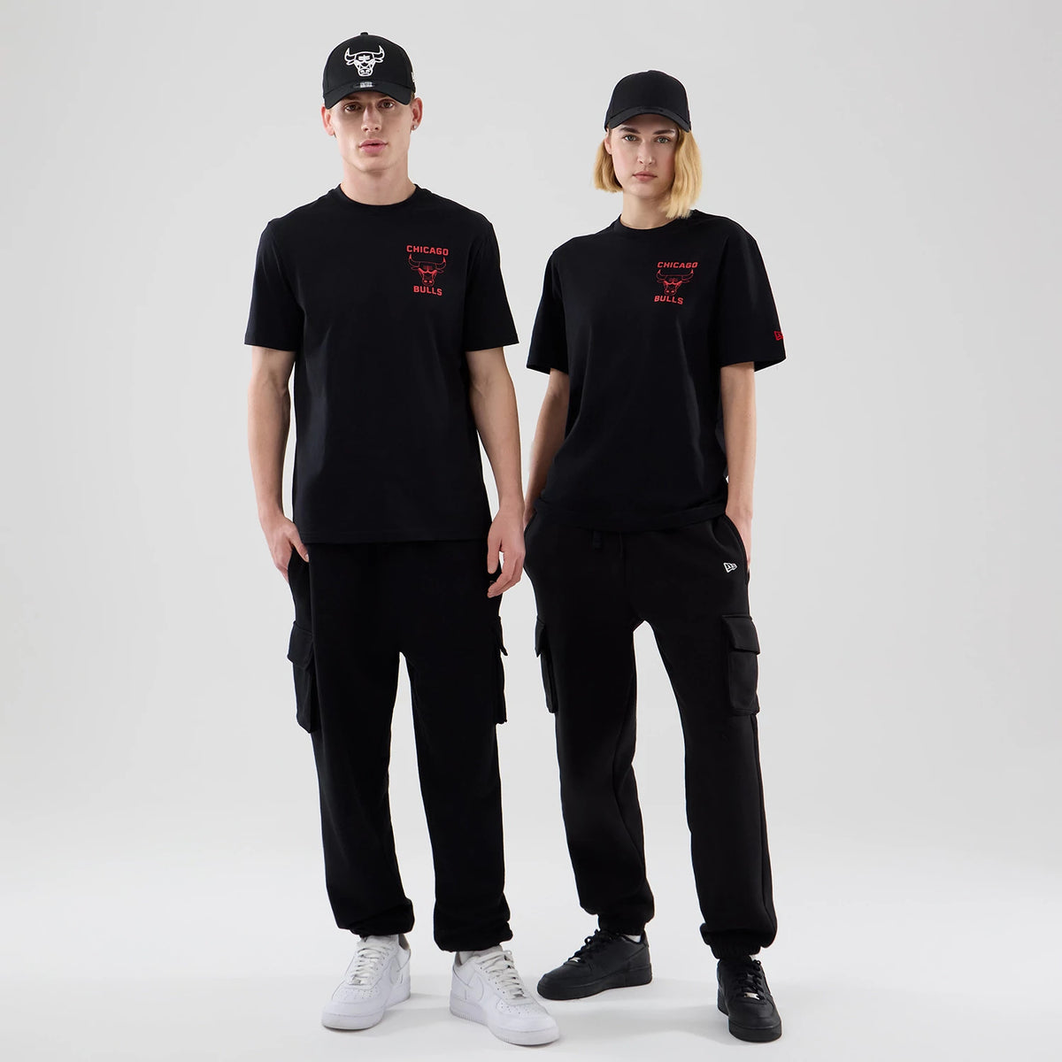 New Era Chicago Bulls NBA Court Graphic Black T-Shirt, front view on-model showing the red embroidered Chicago Bulls logo and lettering on the left chest, styled with black cargo trousers and caps, complemented by contrasting black.