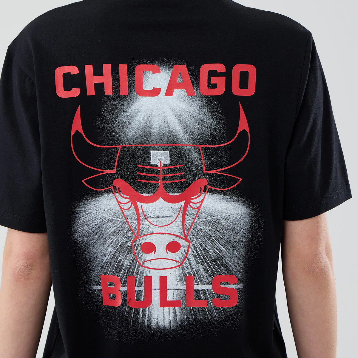New Era Chicago Bulls NBA Court Graphic Black T-Shirt, back view displaying a large red Chicago Bulls logo with the word CHICAGO above and BULLS below, set against an eye-catching white burst graphic on the black fabric.