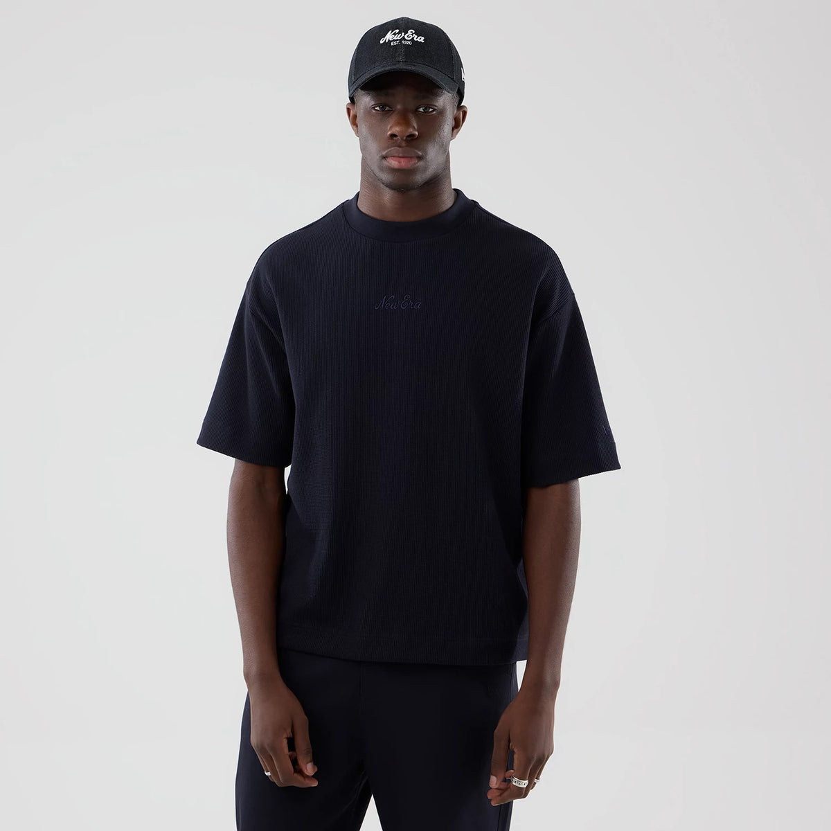 New Era Waffle Navy Boxy T-Shirt, front view on-model showing a relaxed fit with elbow-length sleeves, a embossed New Era logo at the centre of the chest and a slight texture throughout the dark navy fabric.