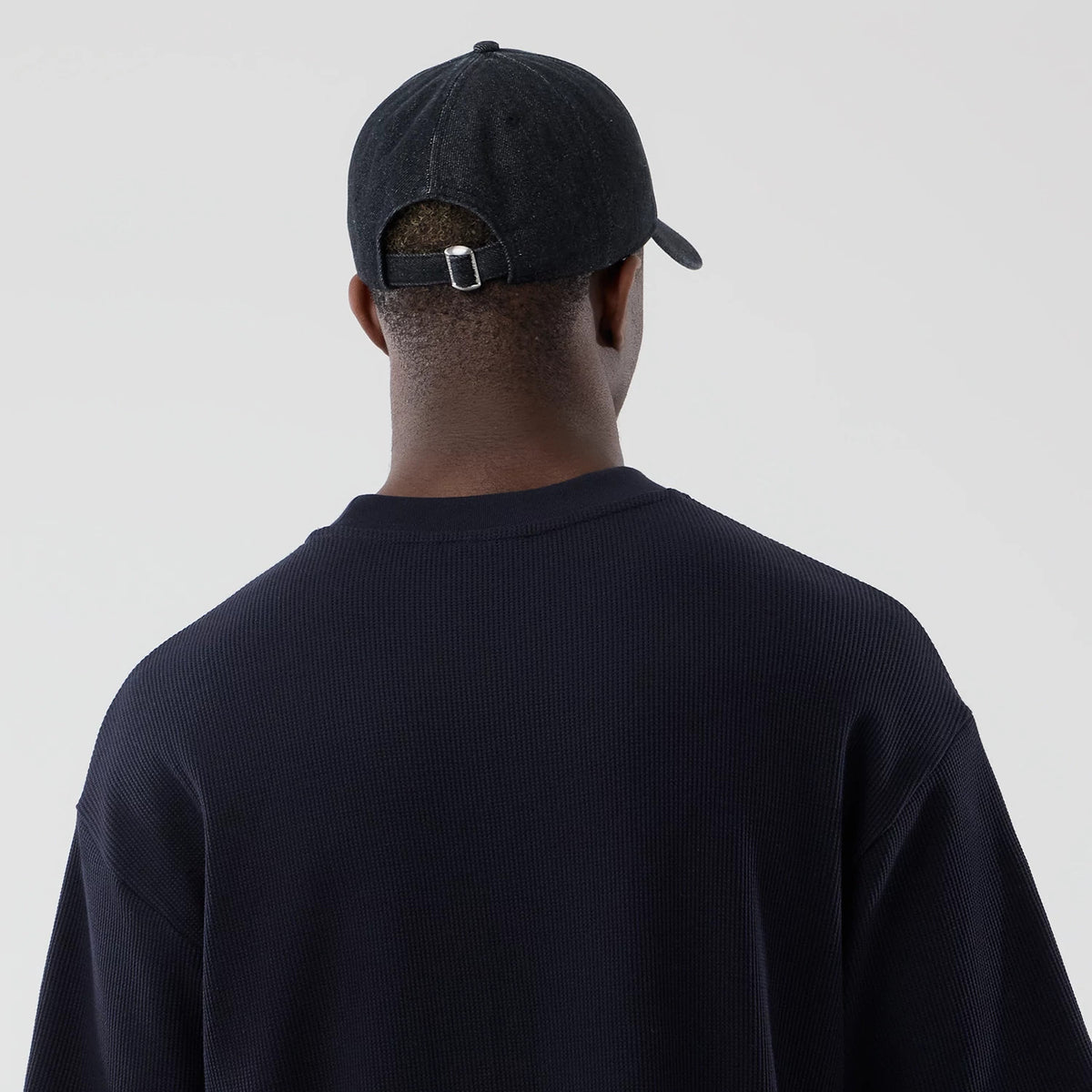 New Era Waffle Navy Boxy T-Shirt, back view on a model wearing a dark cap showing the textured navy fabric across the shoulders, with a rounded neckline and a relaxed fit silhouette seen from the rear.